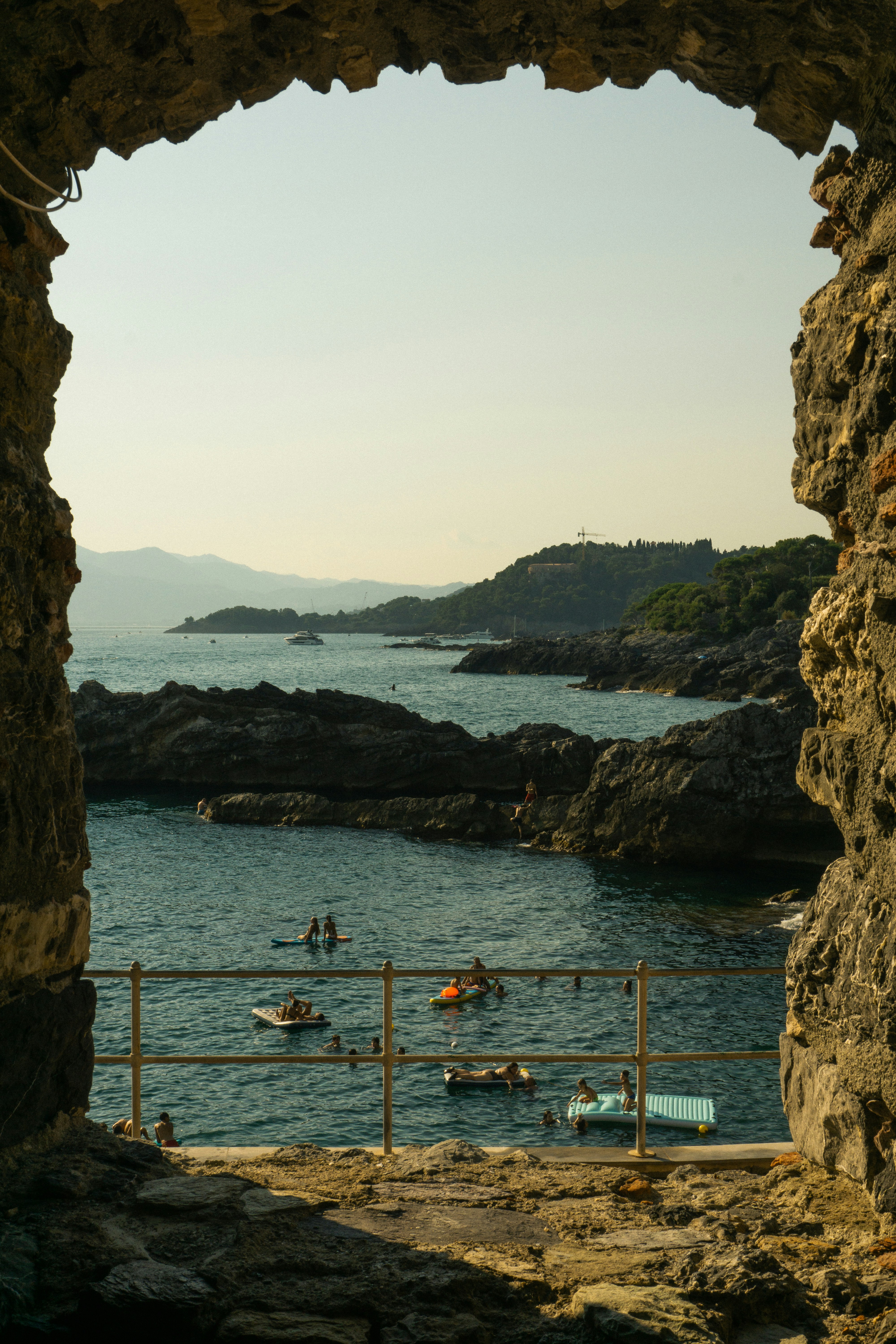 People swimming and relaxing in the sea near rocky coast.