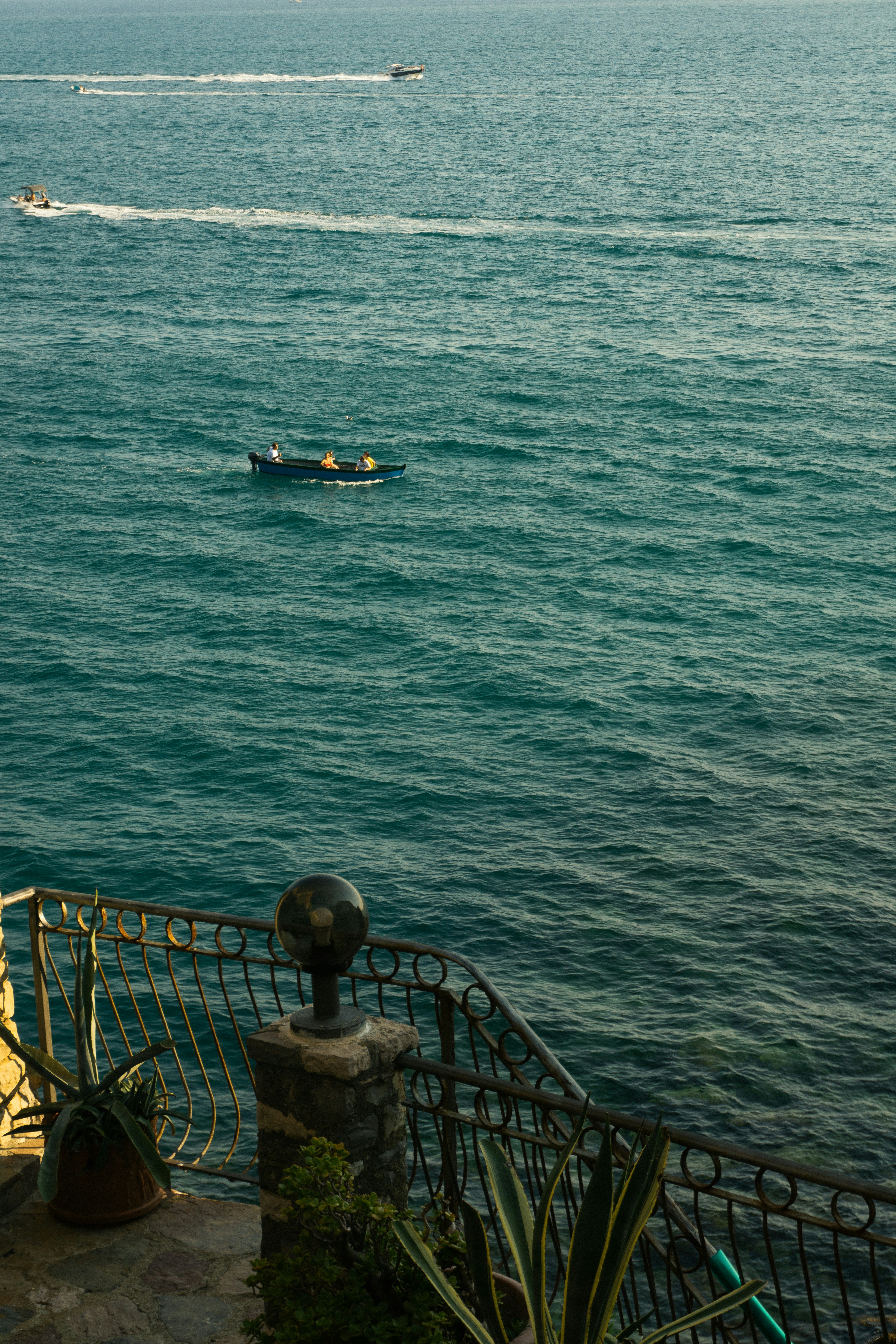 Boats on the blue ocean near a railing.
