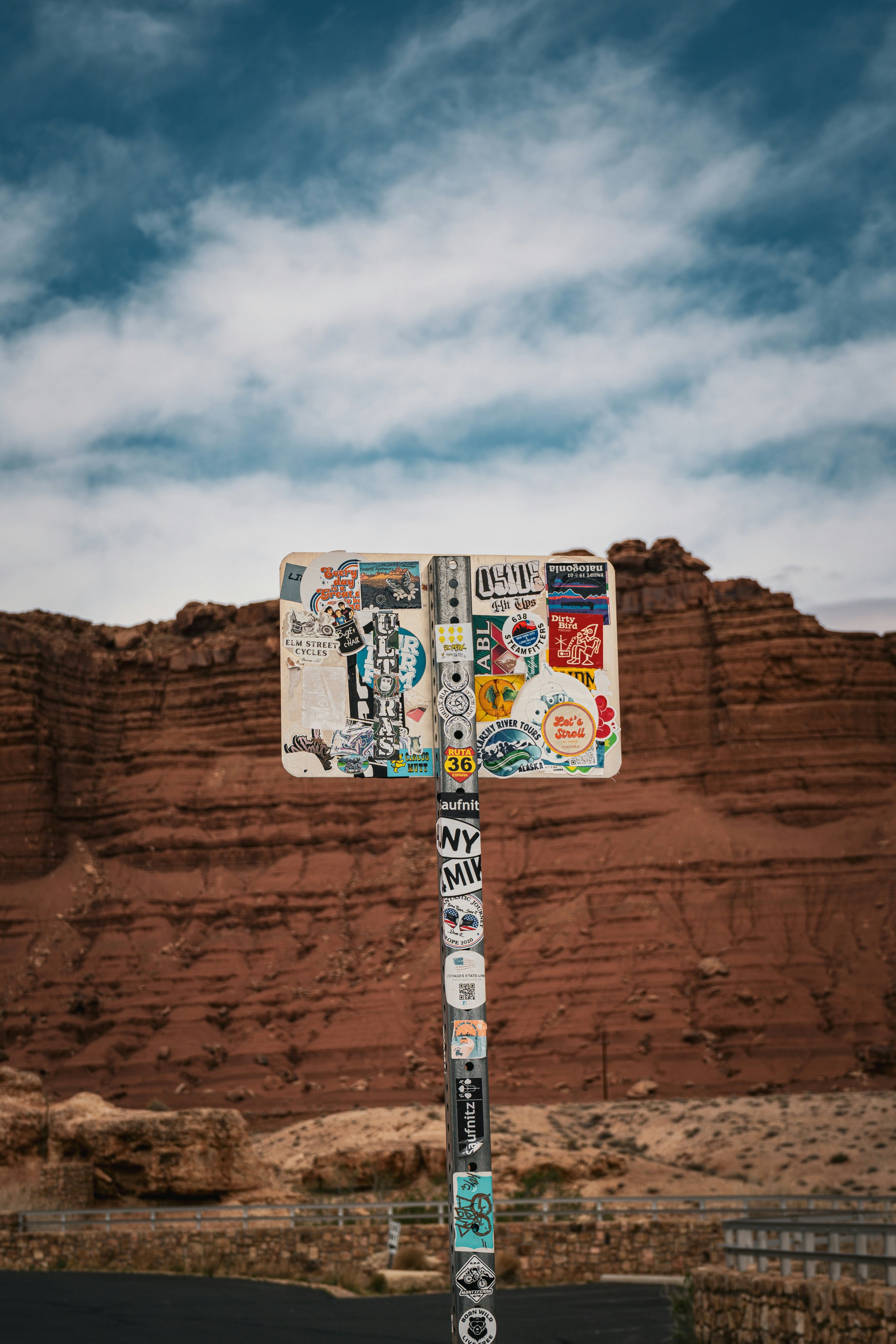 Cartel cubierto de pegatinas contra un acantilado de roca roja.