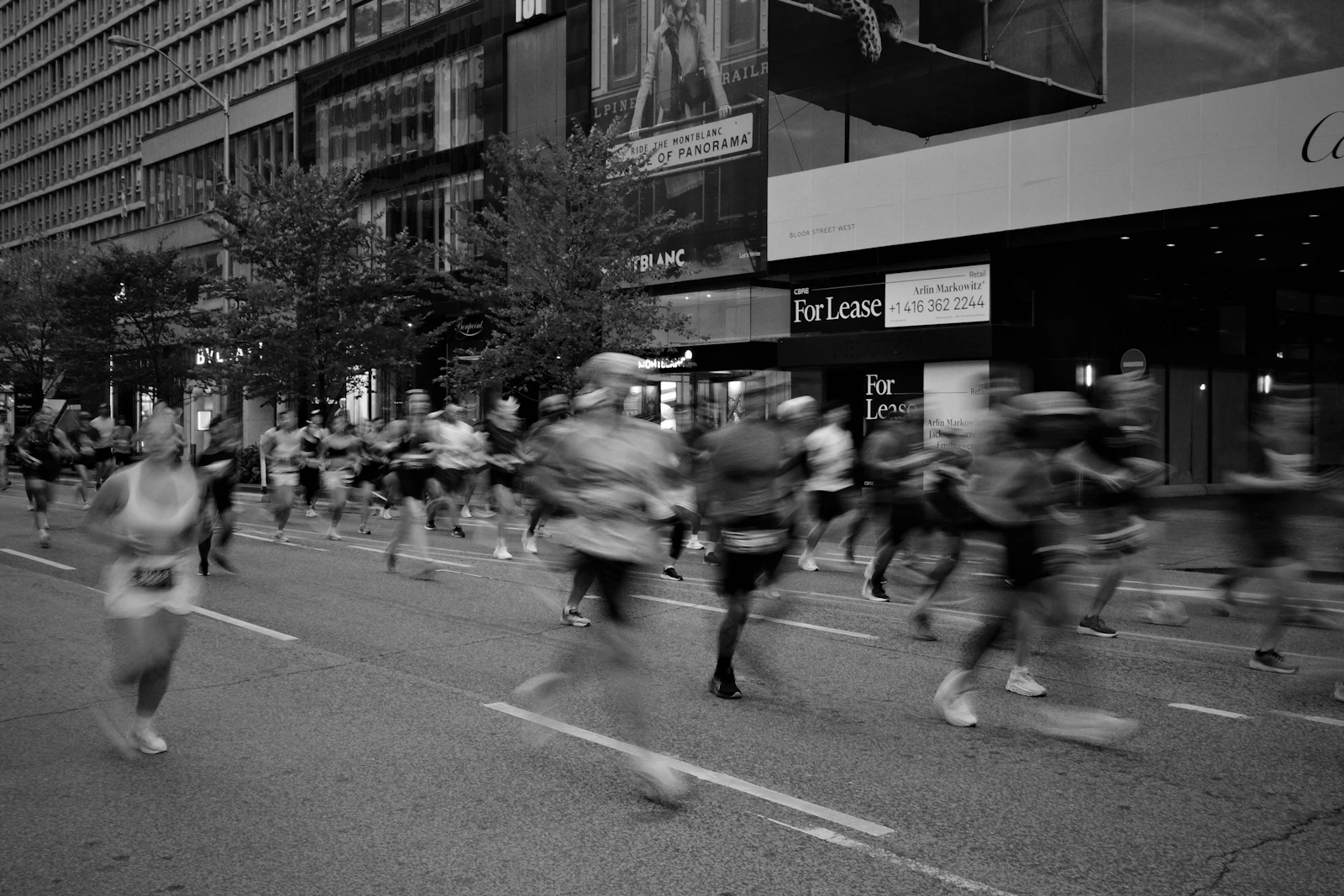 Pelotão de corredores numa maratona de cidade, em pleno esforço na estrada