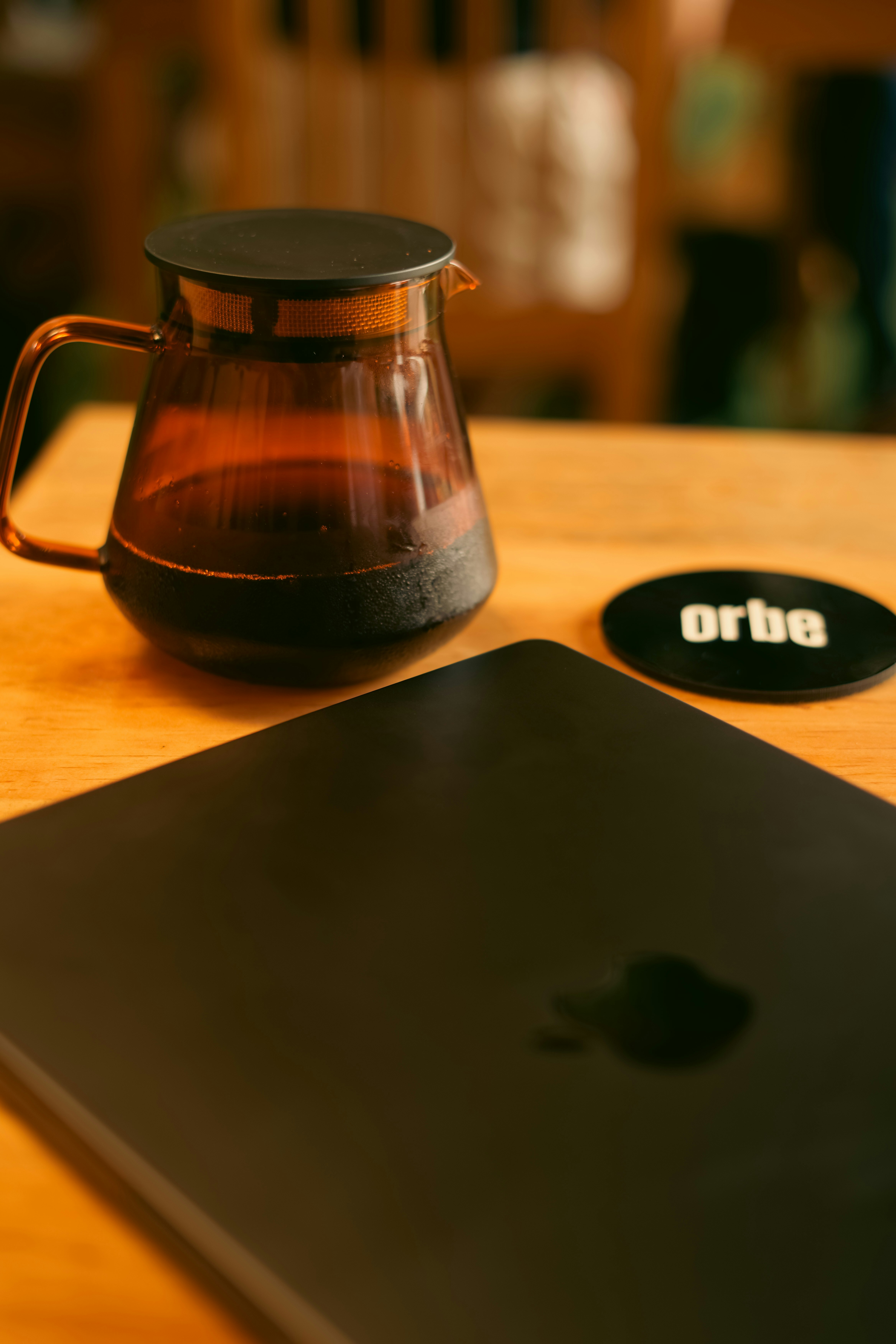 Glass coffee pot and laptop on wooden table