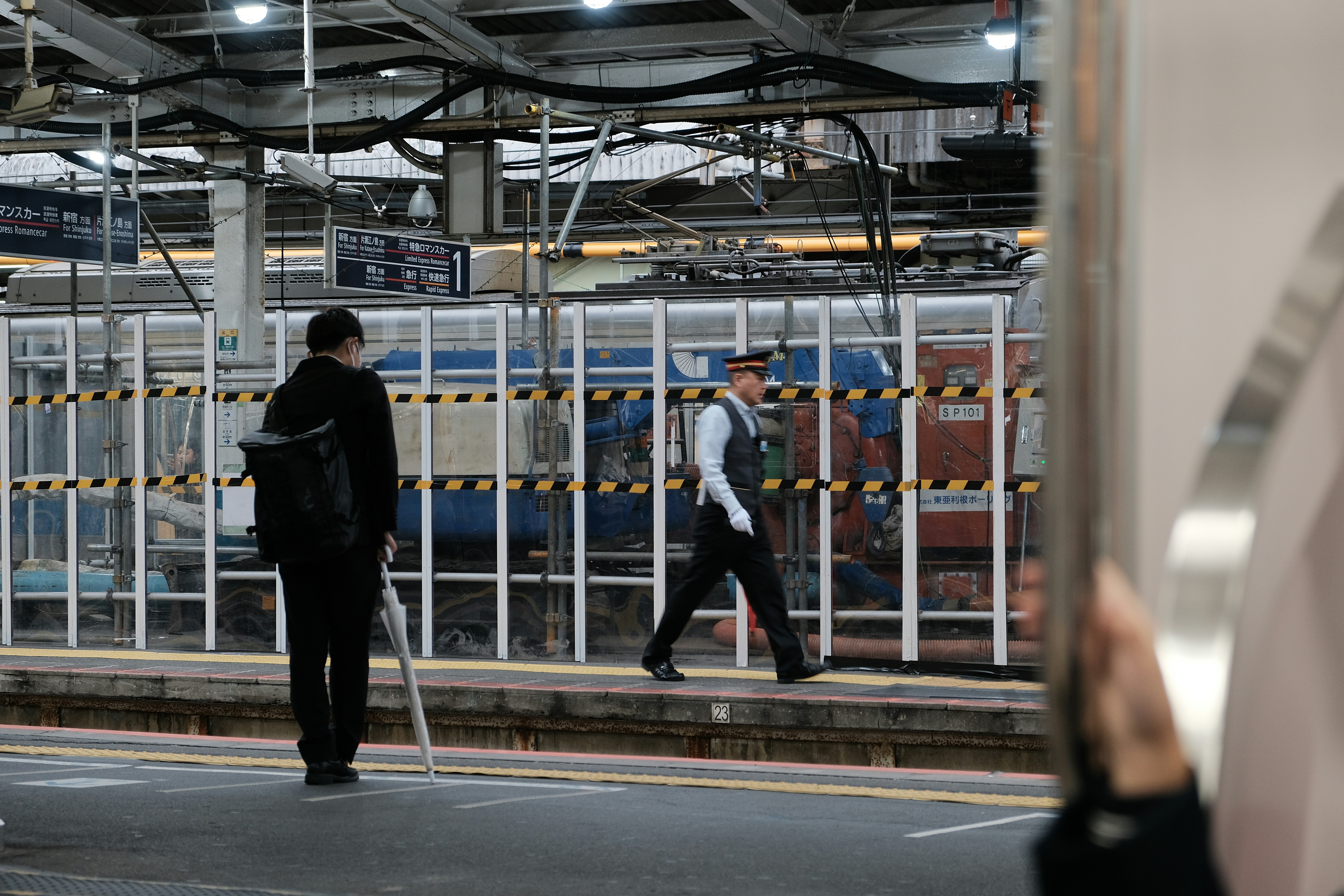 Man waiting on a train platform beside a fence