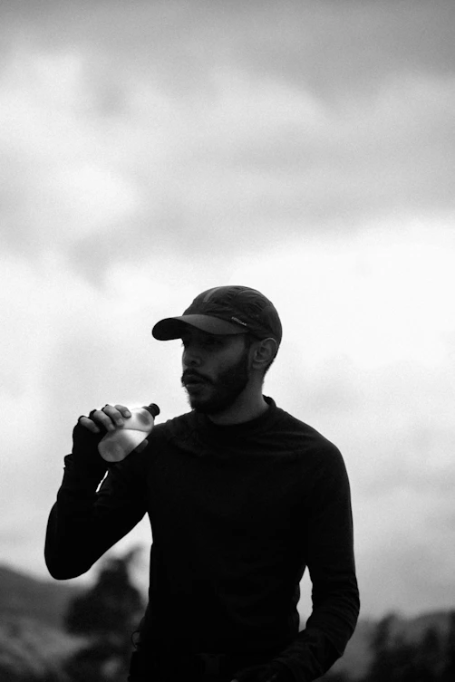 Man in cap drinking water from bottle outdoors
