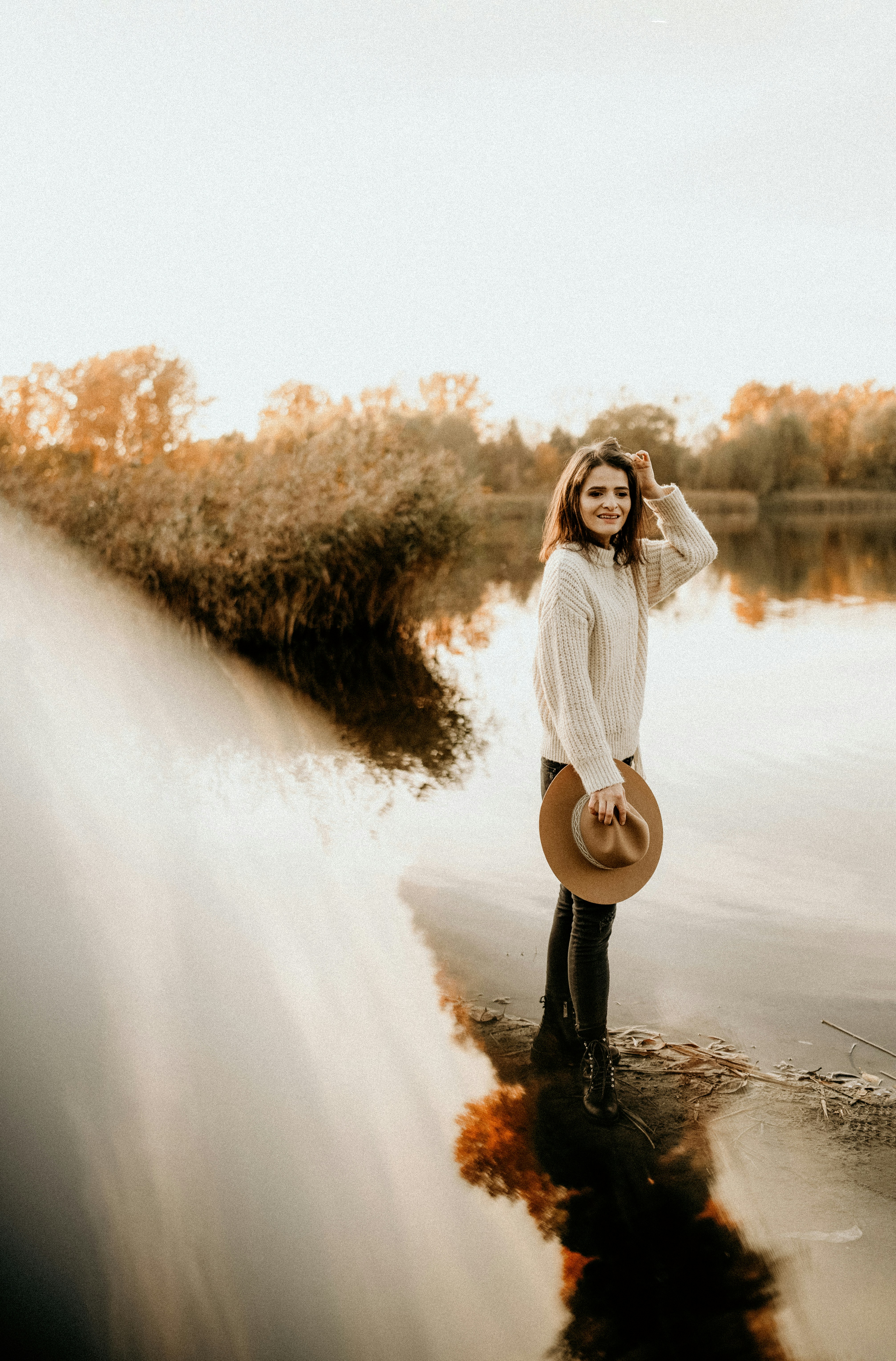 Woman standing by a calm lake at sunset