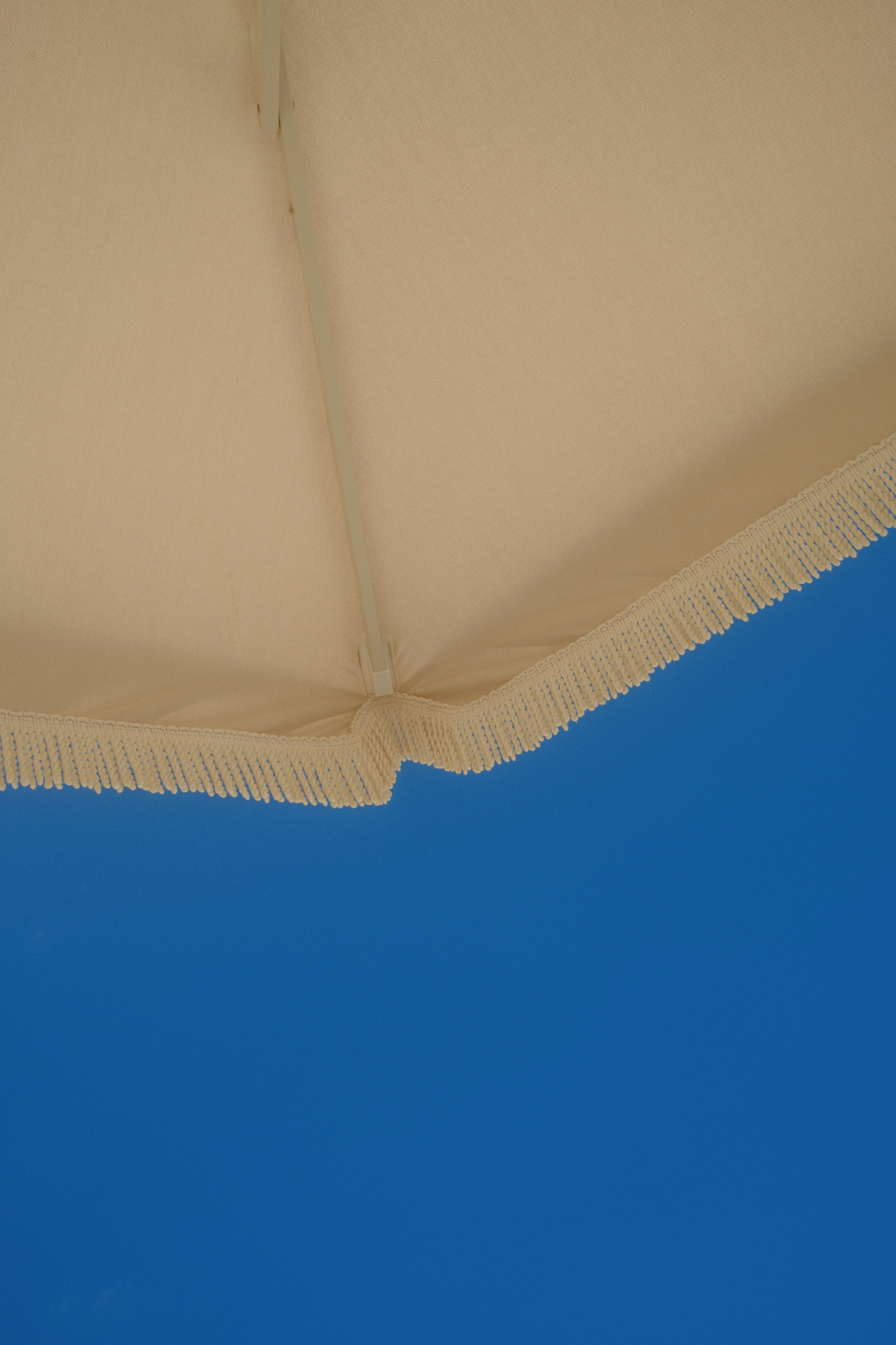 Frange de parapluie crème sur un ciel bleu vif