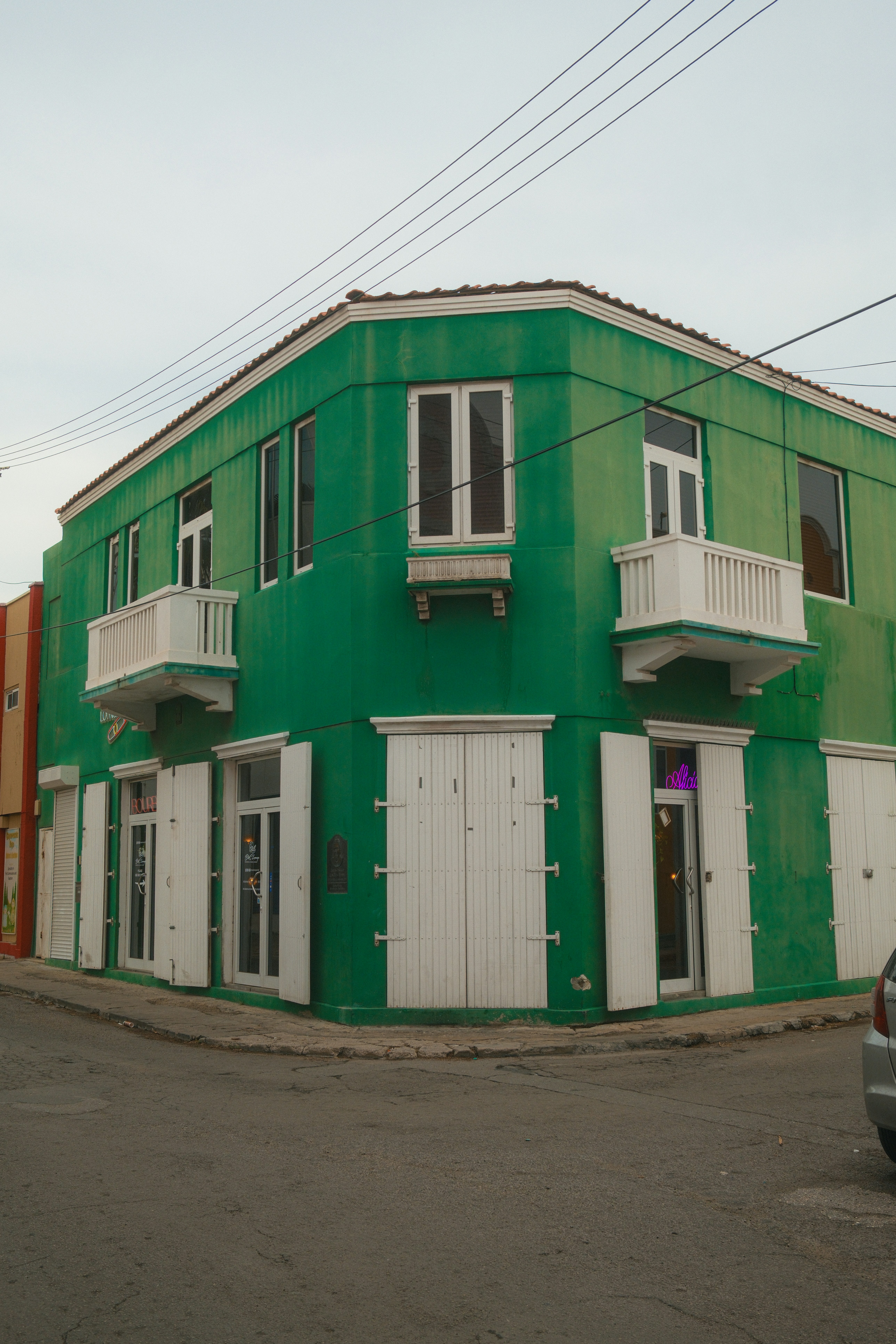 Bâtiment vert avec volets et balcons blancs