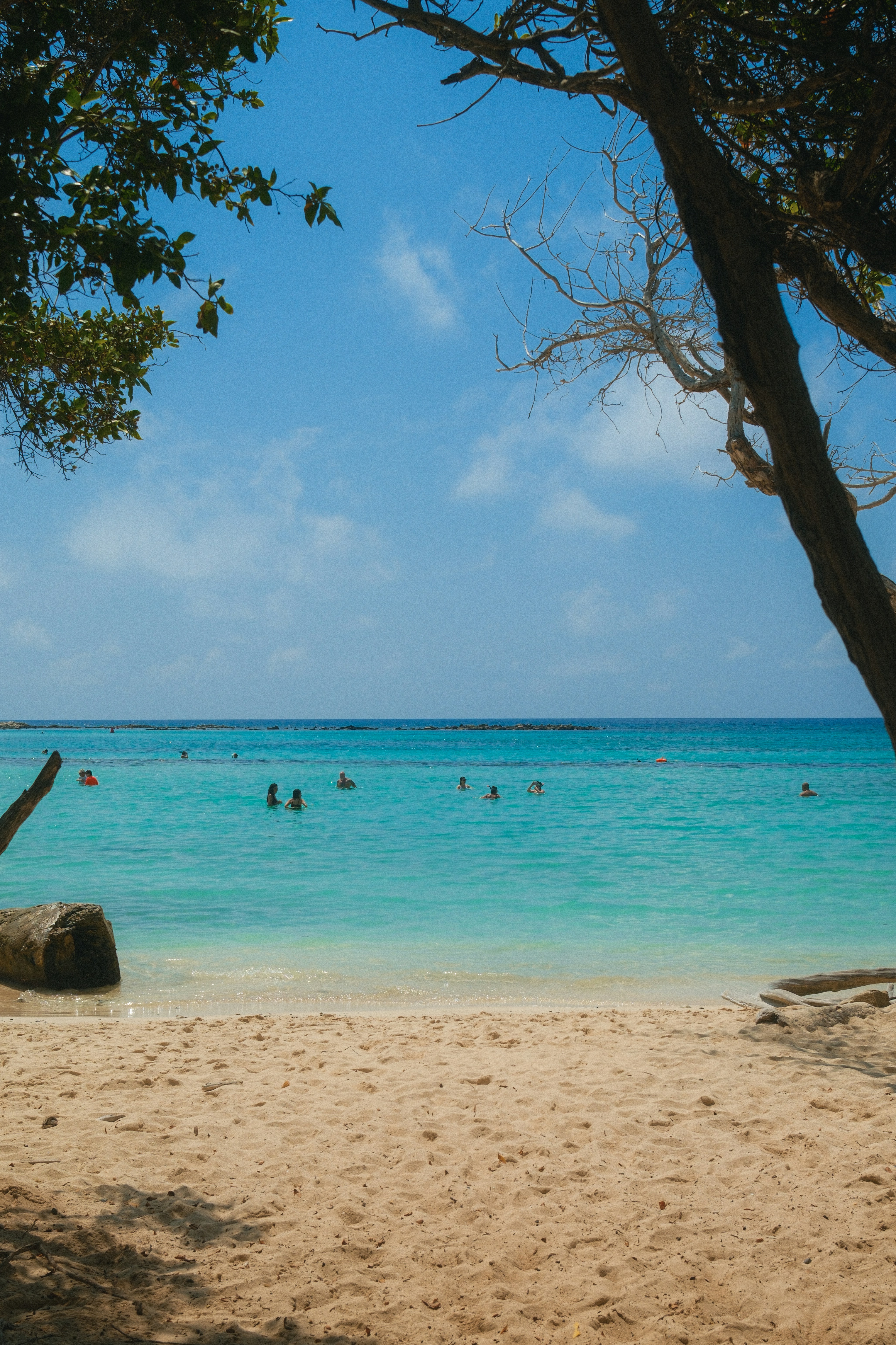 Des gens nageant dans un océan turquoise clair sous un ciel bleu.