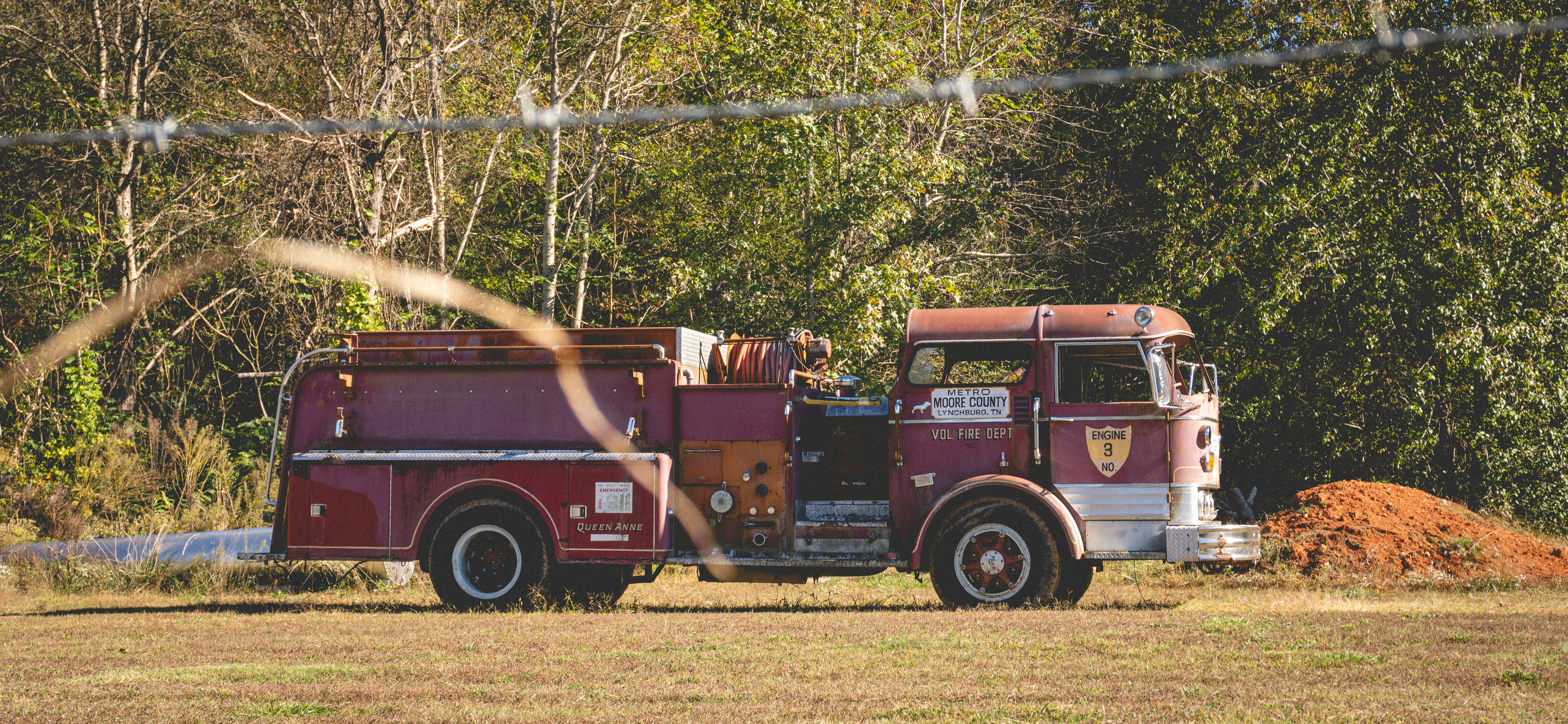 Old red fire truck parked in a grassy field.
