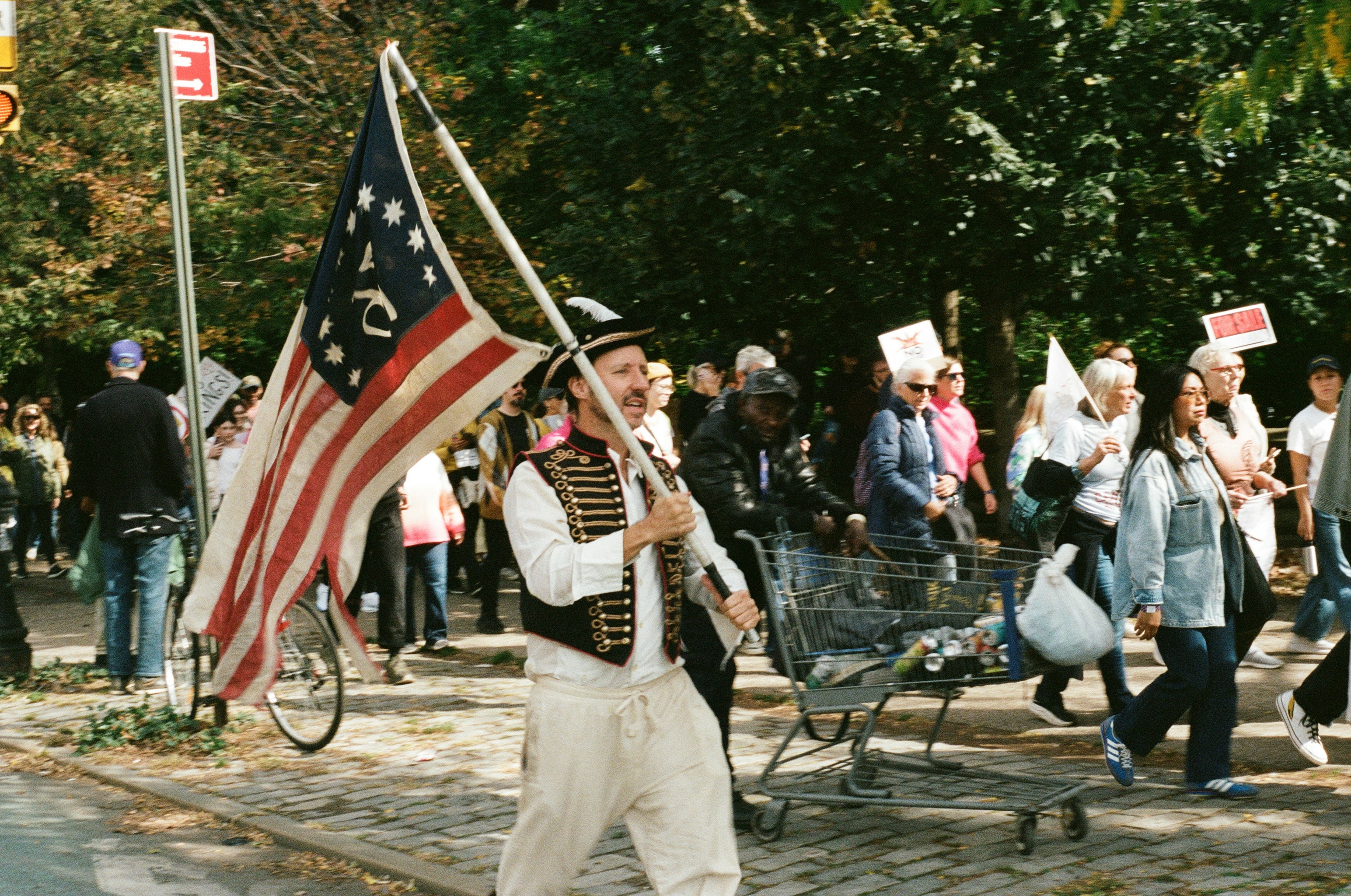 Man in historical costume carries colonial flag in a parade.