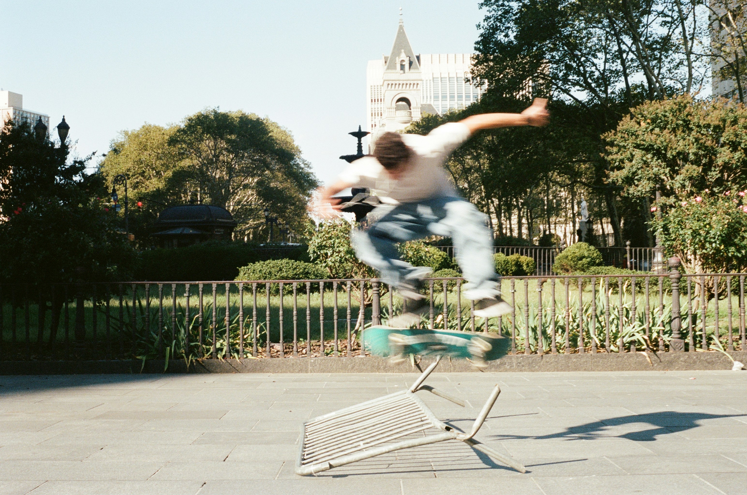 Skateboarder performs trick over metal bar outdoors