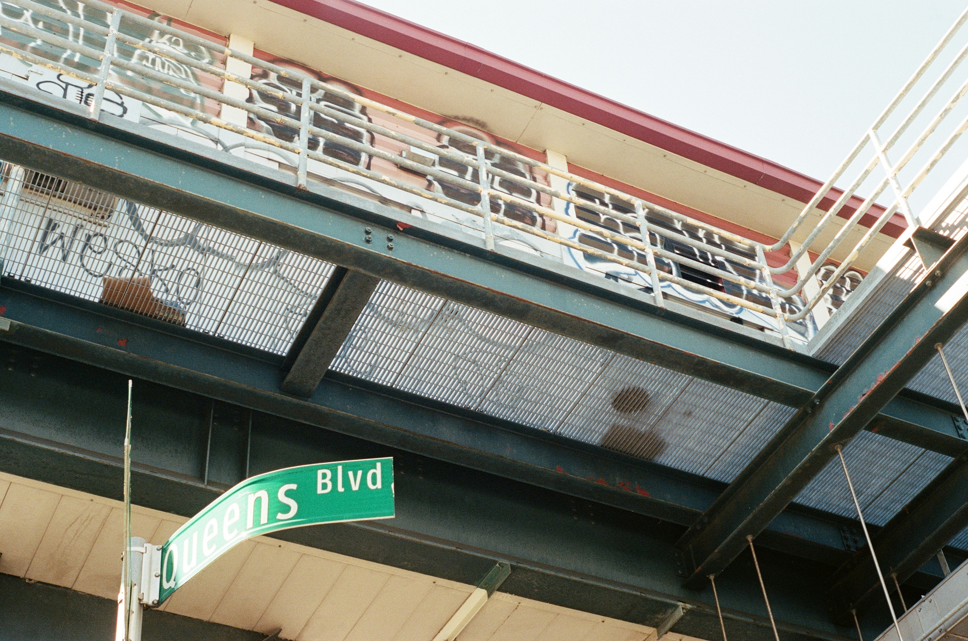 Street sign for queens blvd under elevated structure