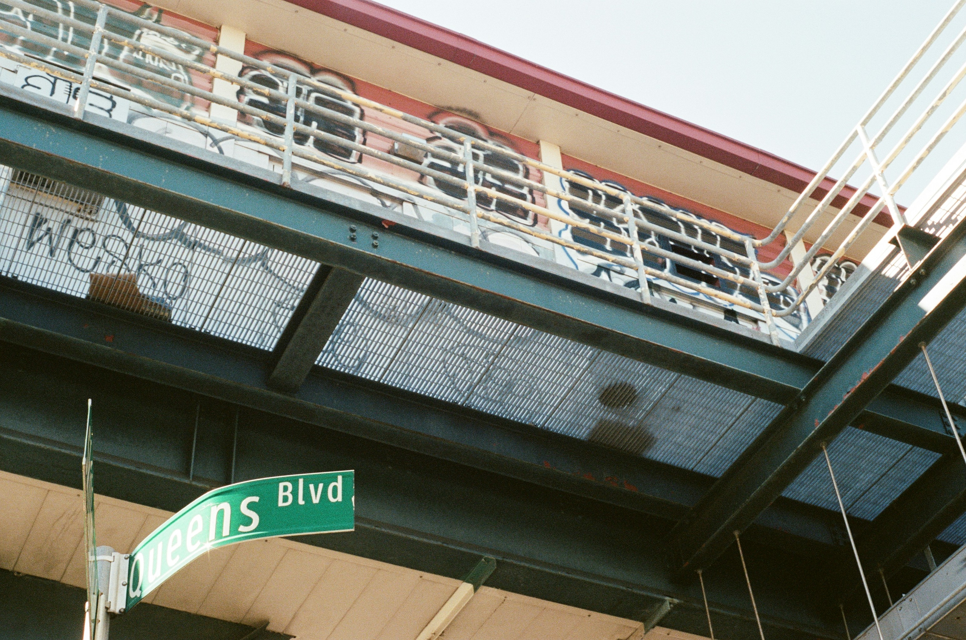 Graffiti on an elevated train station with street sign.