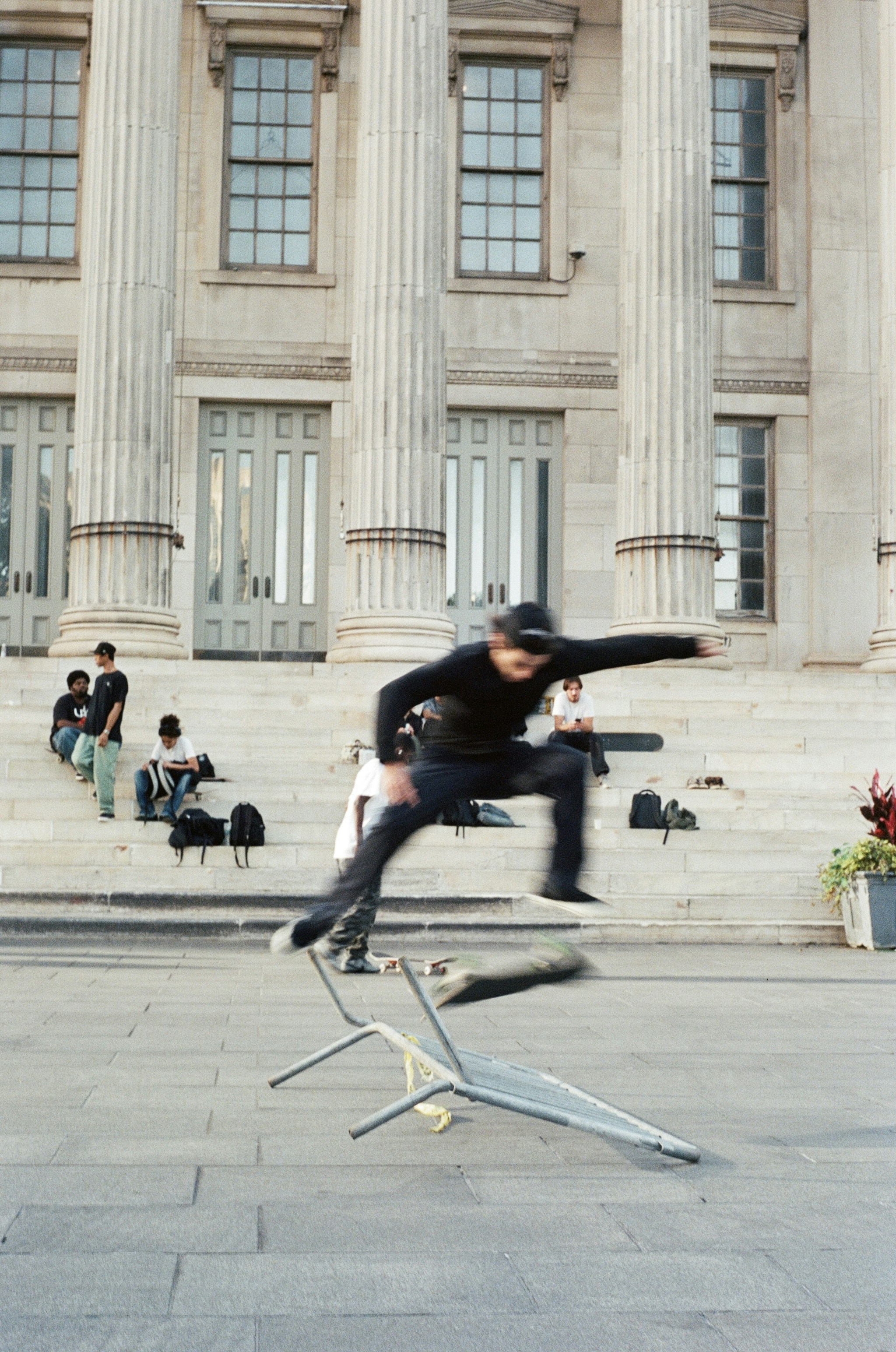 Skateboarder jumps over a chair on steps.