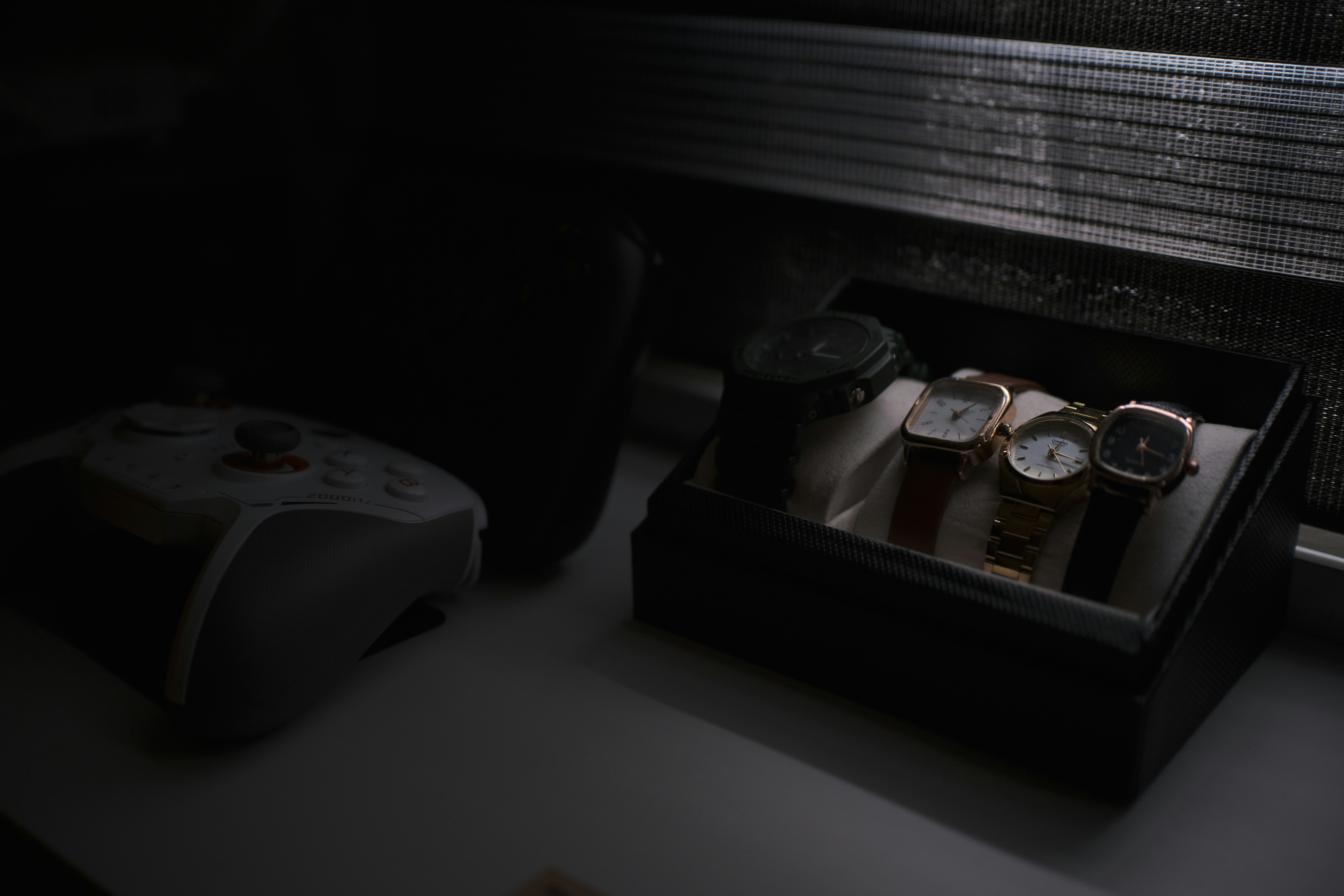 Four watches in a display box near a controller.
