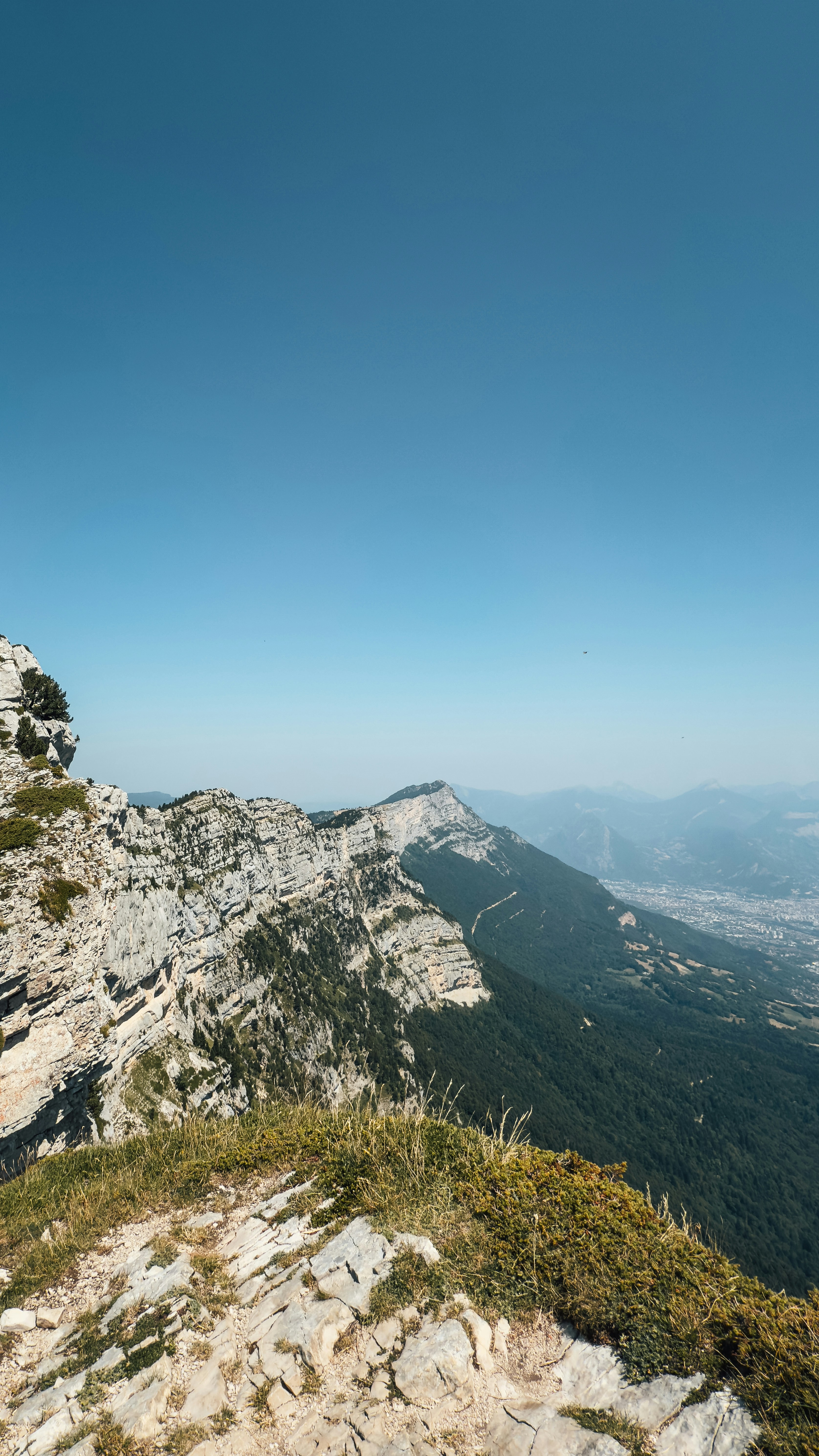 Rocky mountain ridge overlooking a valley and distant city.