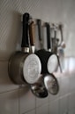 Pots and utensils hanging on a kitchen wall.