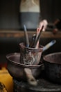 Paintbrushes in a metal pot with other supplies