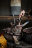 Paintbrushes in a metal pot with other supplies