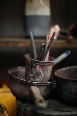 Paintbrushes in a metal pot with other supplies