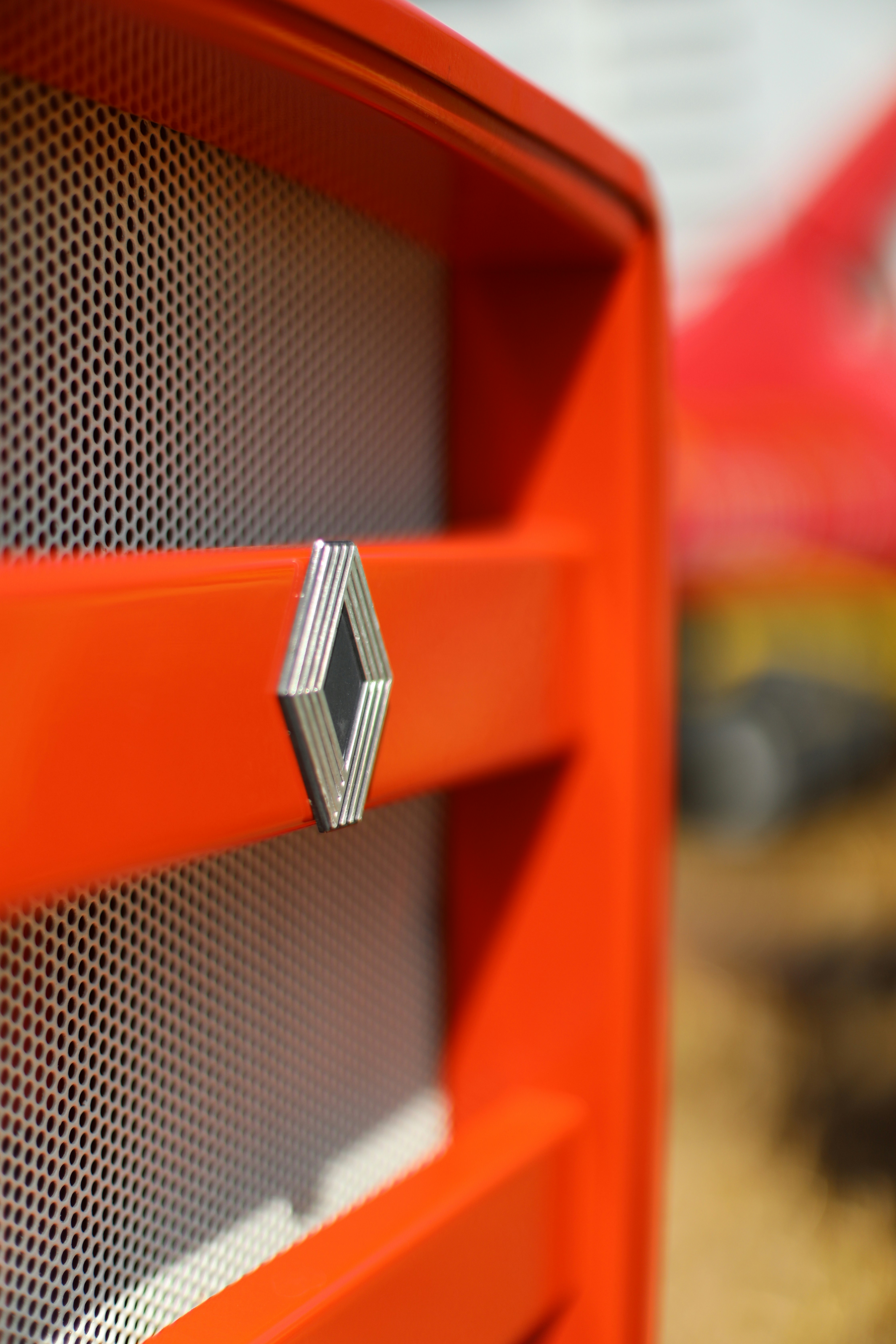 Close-up of an orange vehicle grille with logo