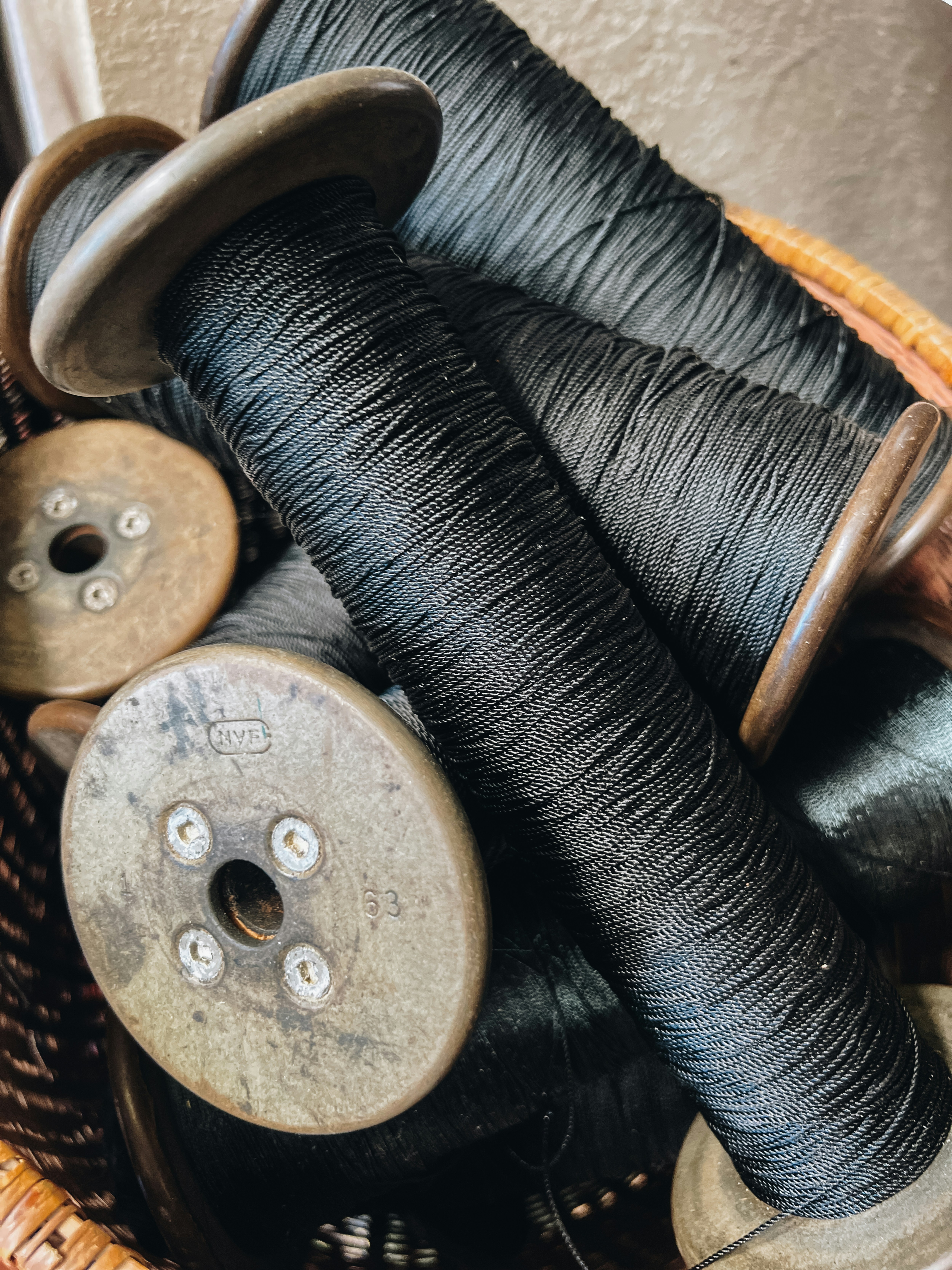 Close-up of vintage black thread spools in basket