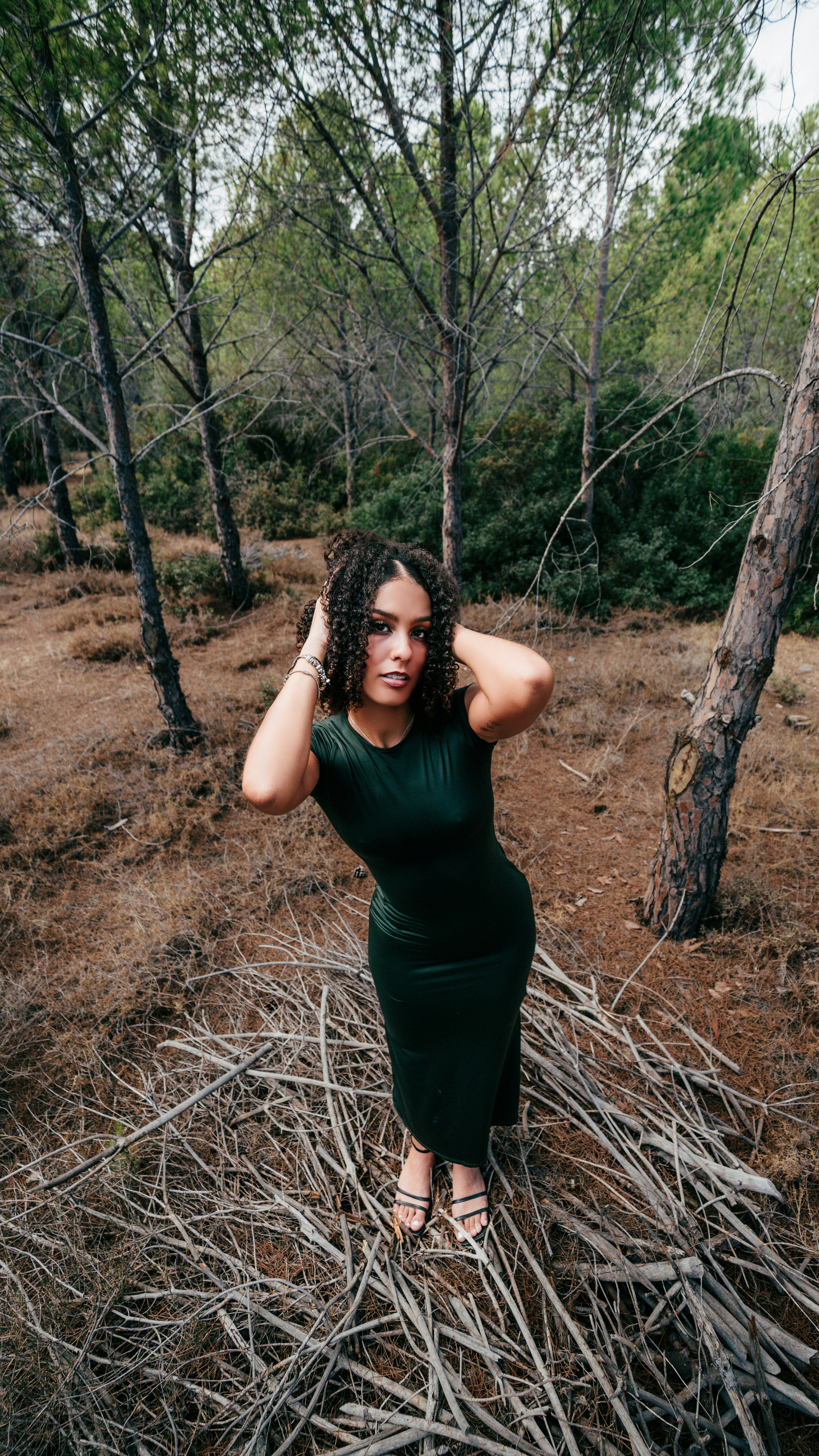 Woman in green dress standing in a dry forest