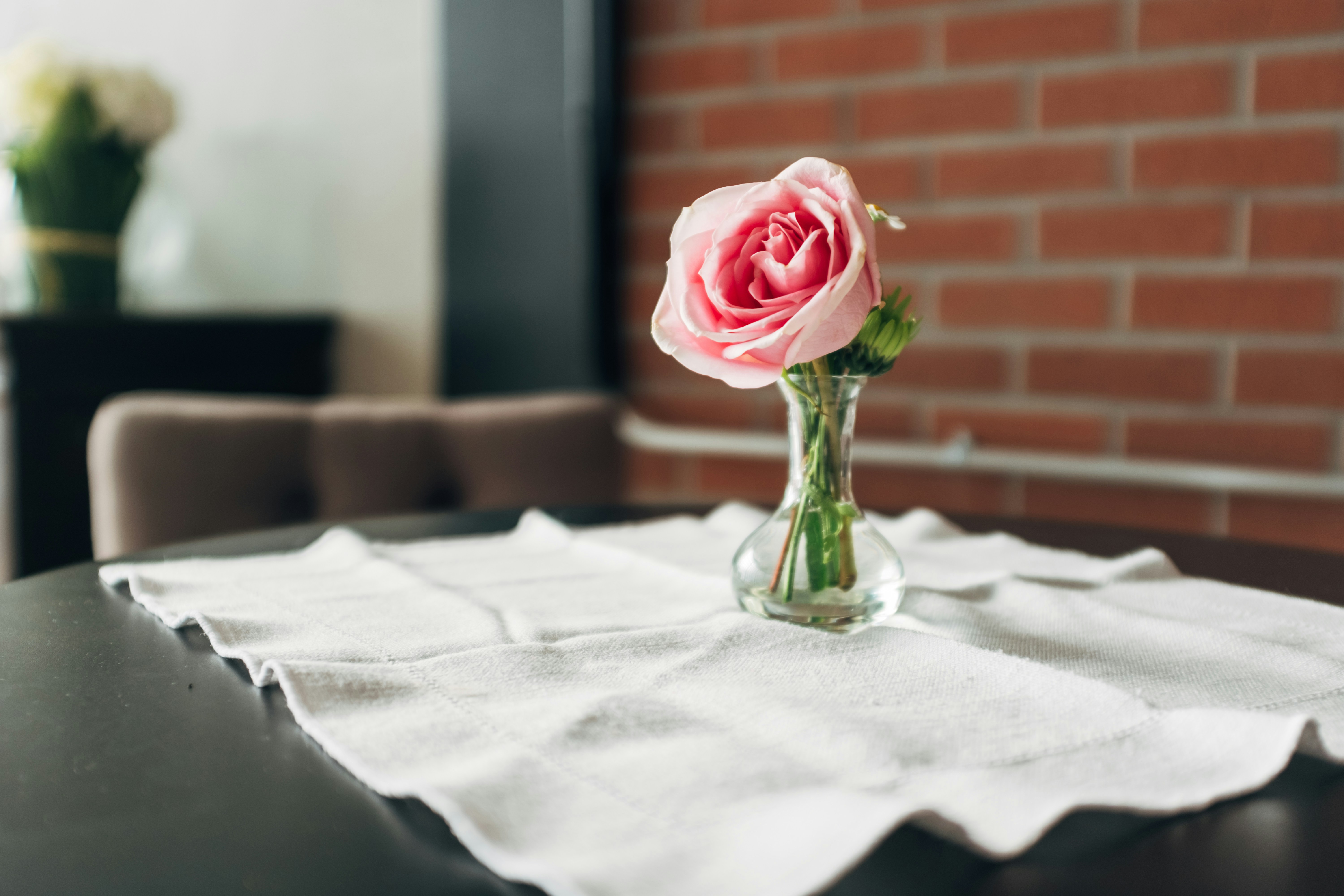 Une seule rose rose dans un vase sur une table.