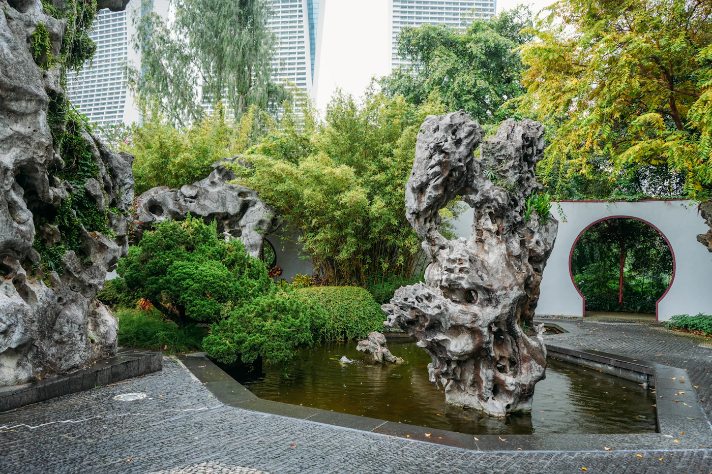 A quiet garden with still water, stone, and soft greenery, evoking calm reflection.
