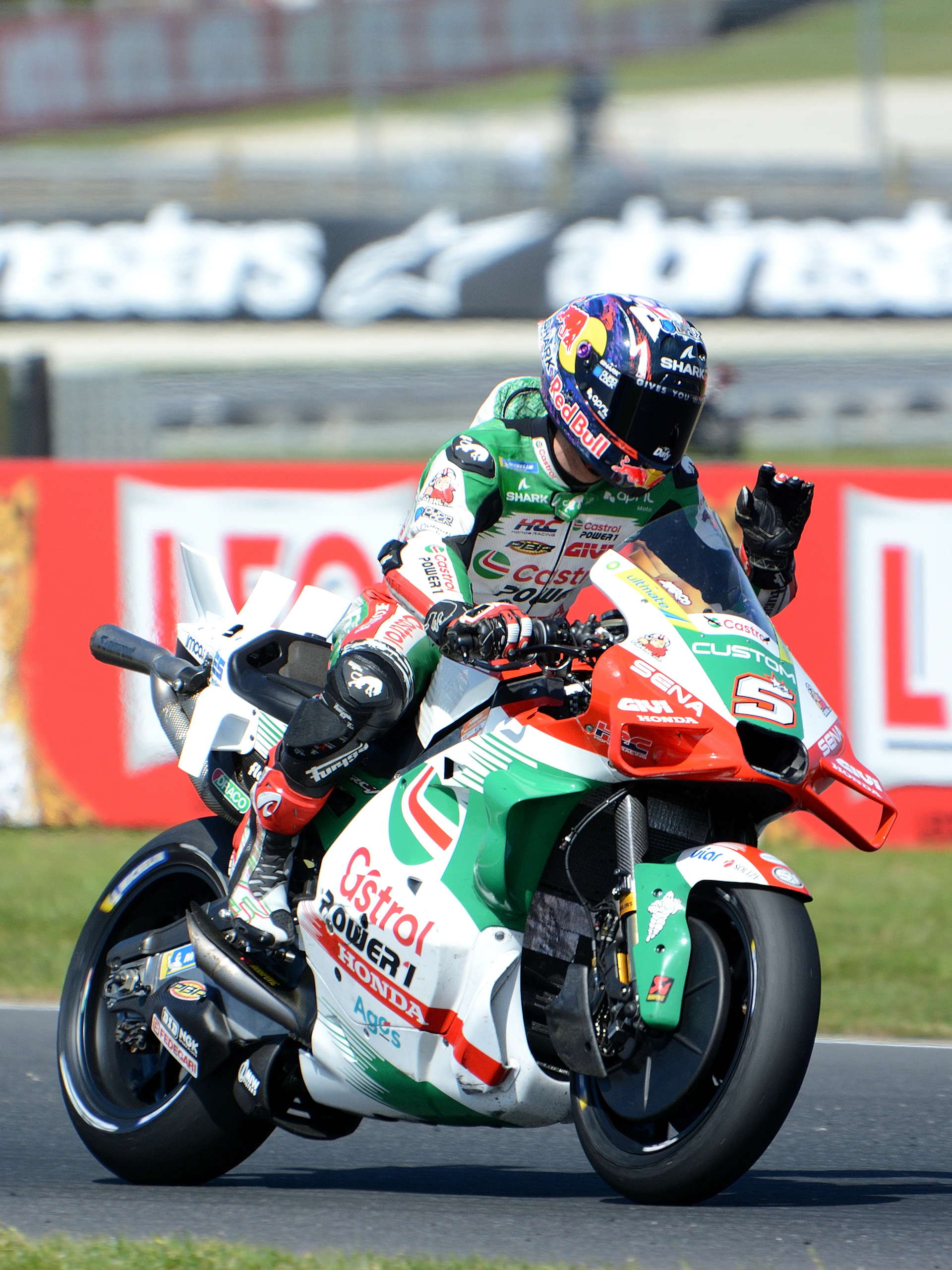 Motorcyclist waves while riding a racing bike