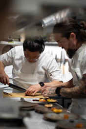 Two chefs preparing food in a kitchen.