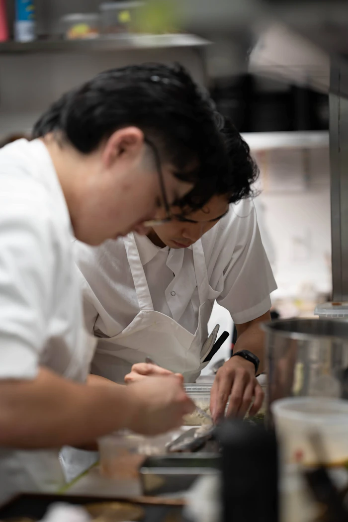 Chef mengenakan celemek AFUN sedang menata hidangan