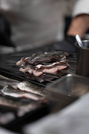 Raw fish skewers being prepared on a grill.