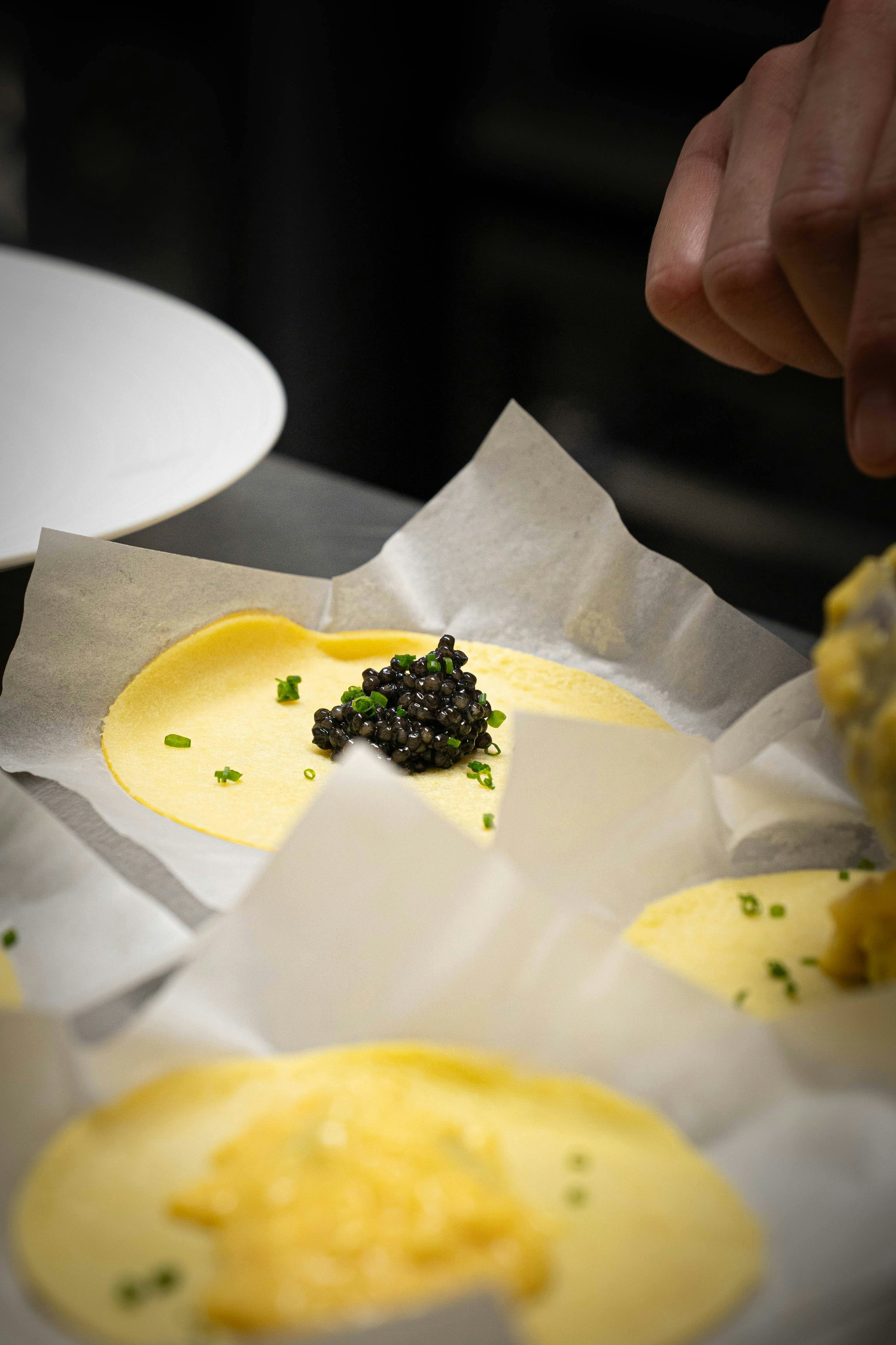 Der Küchenchef garniert das Essen mit schwarzem Kaviar und Schnittlauch.