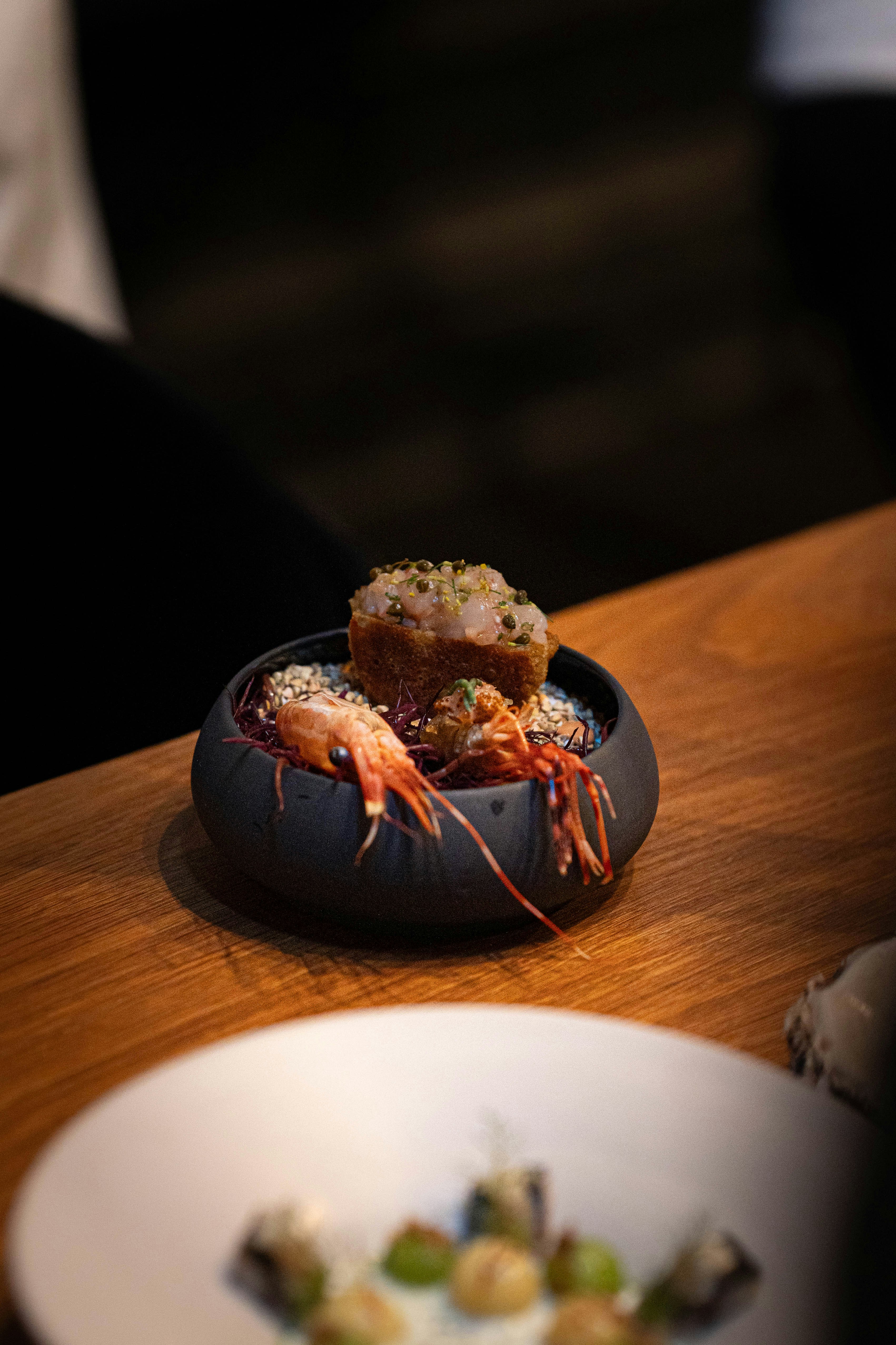 Gourmet dish with shrimp and a small cake.