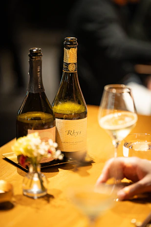 Two bottles of wine and a glass on a table.