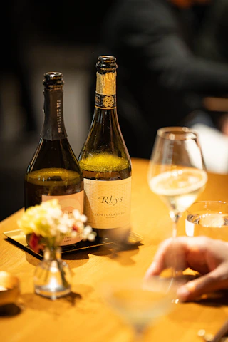 Two bottles of wine and a glass on a table.