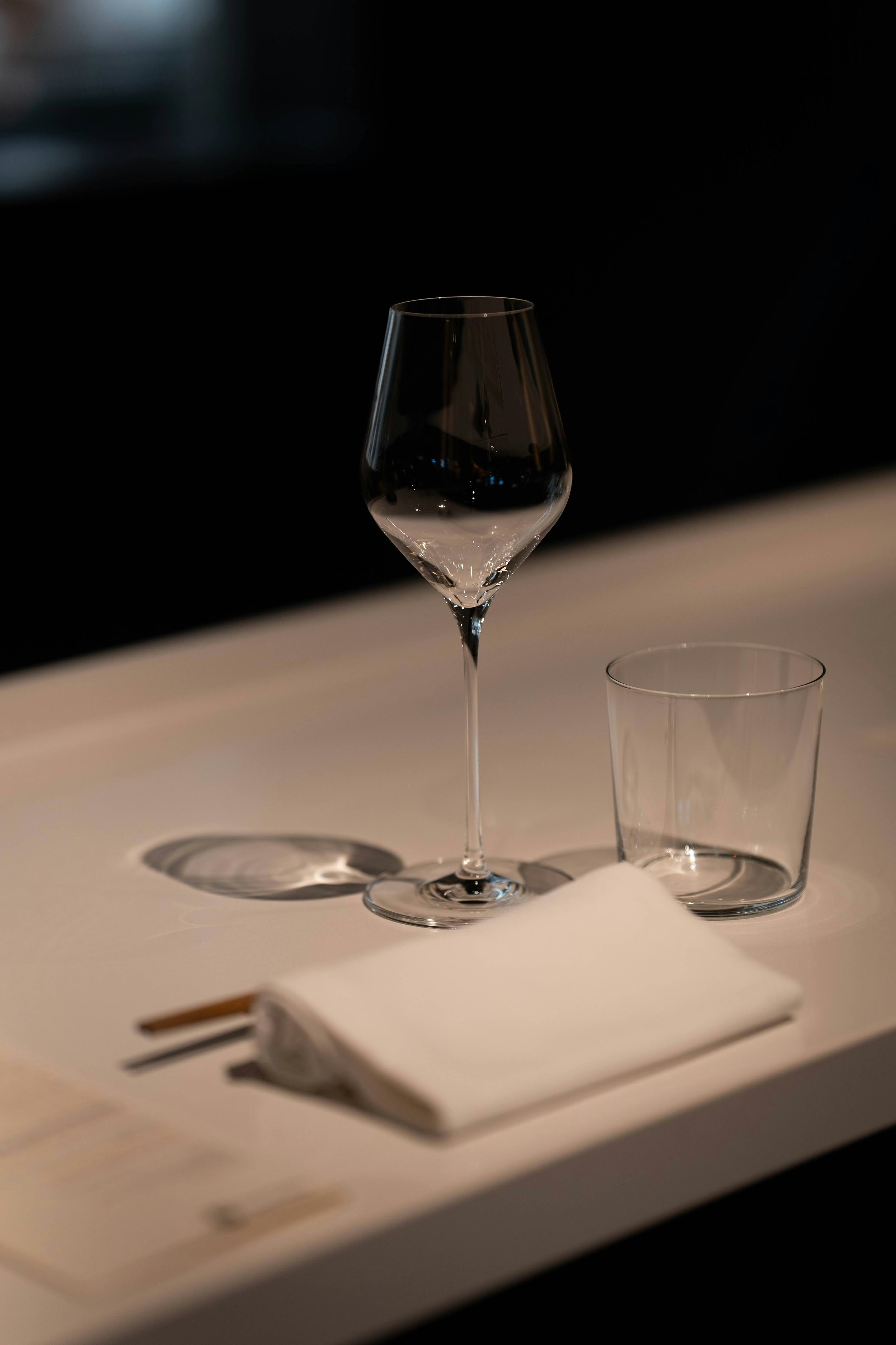 A wine glass and tumbler with a napkin on table.