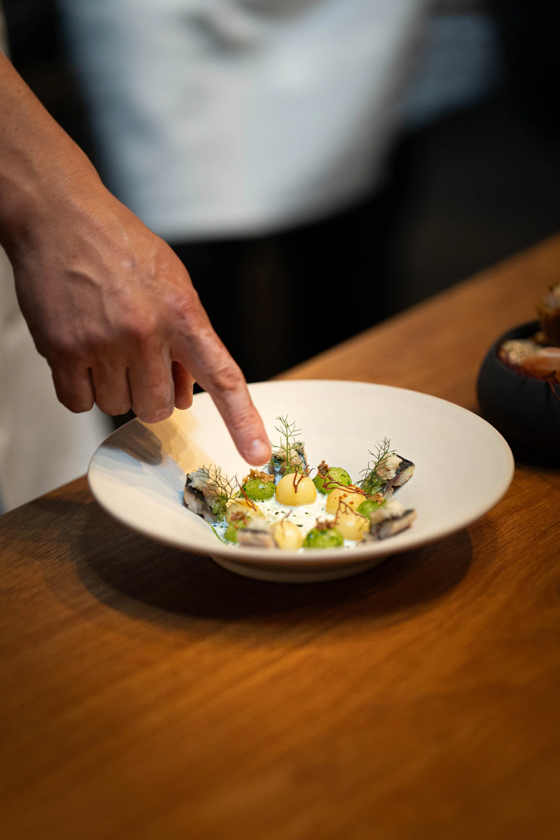 Mano terminando un plato de mariscos con eneldo