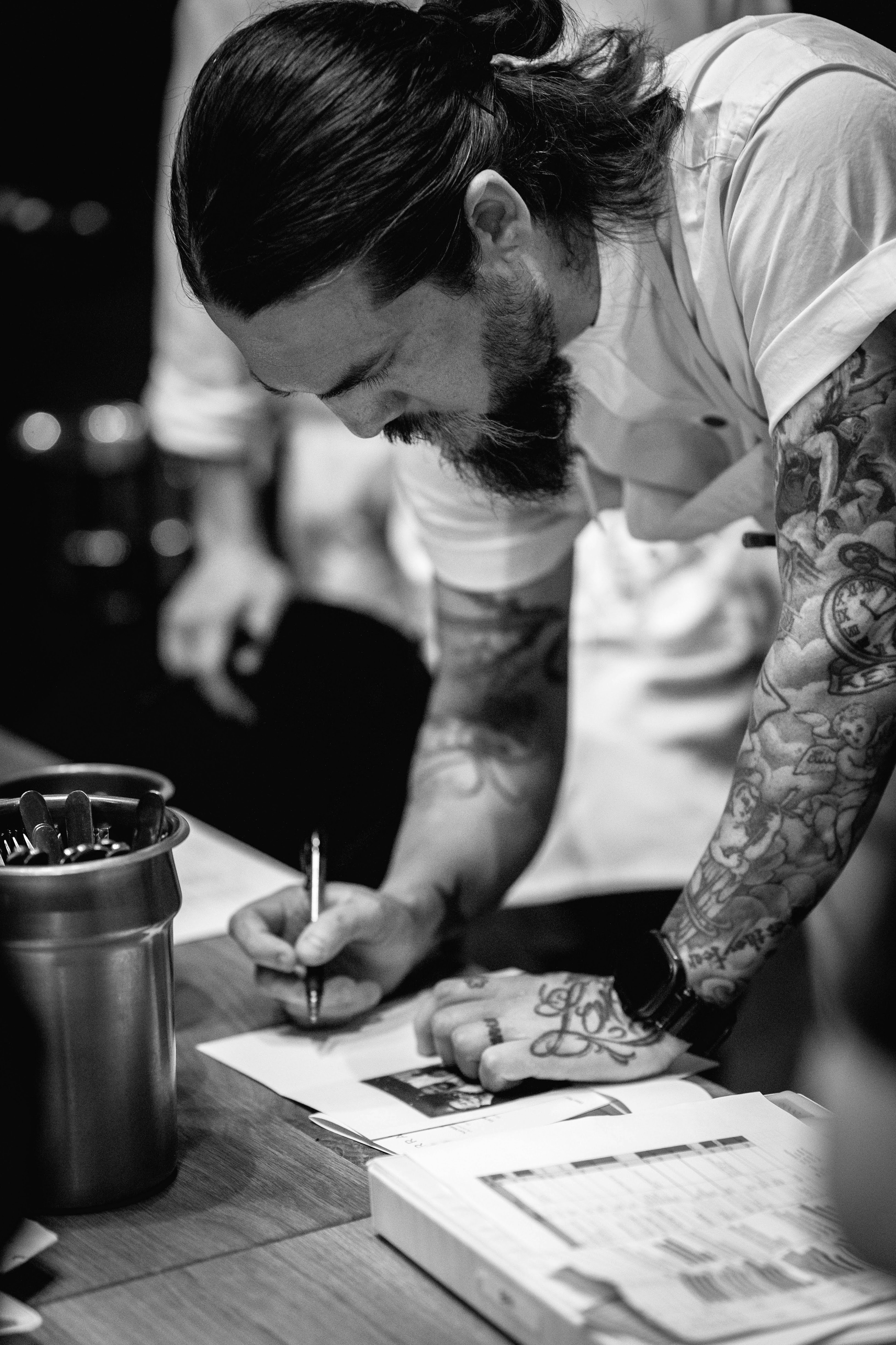 Chef with tattoos writing on paper