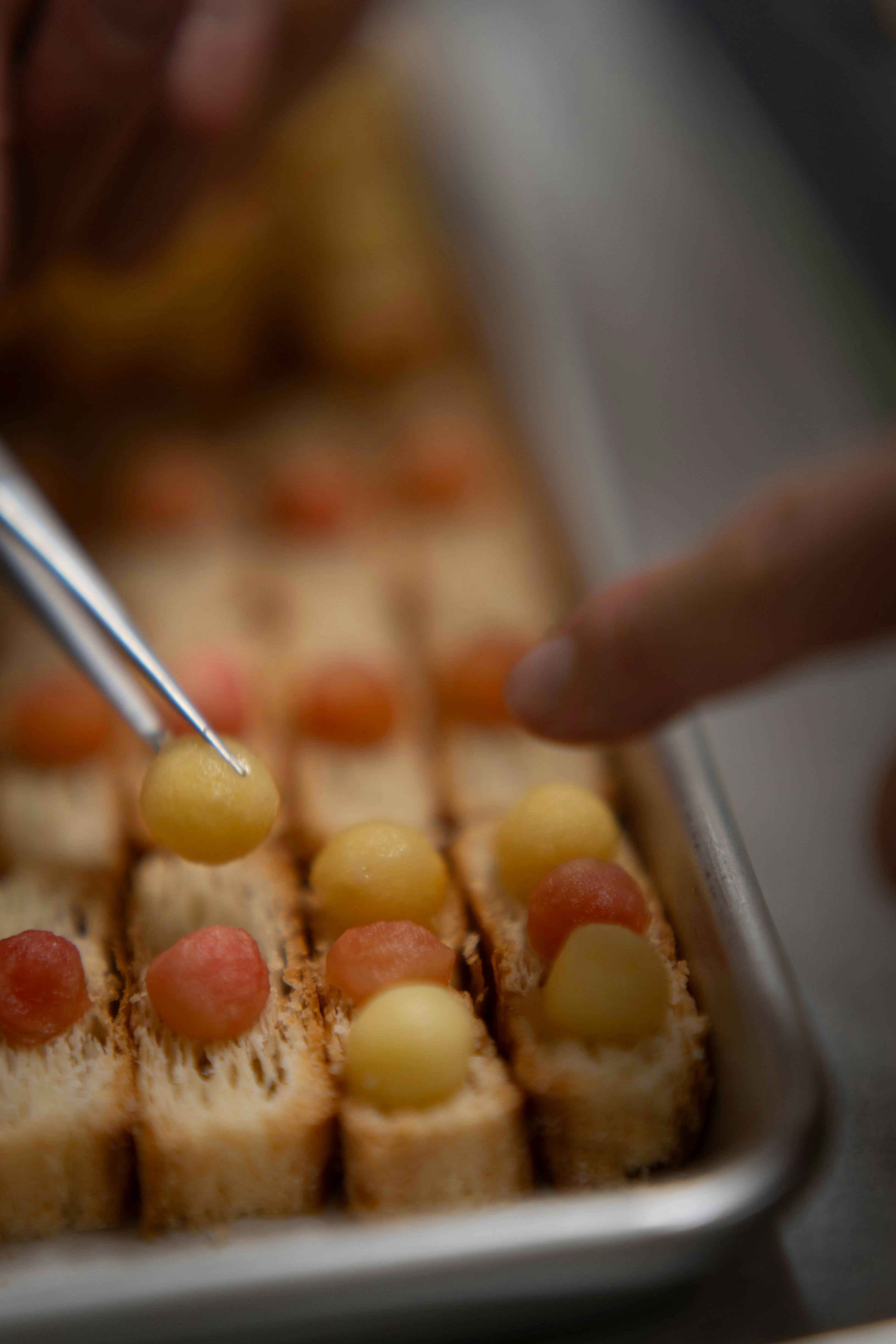 Chef places small yellow spheres on appetizer bites