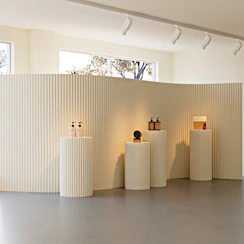 Cream display stands with products in a minimalist room.