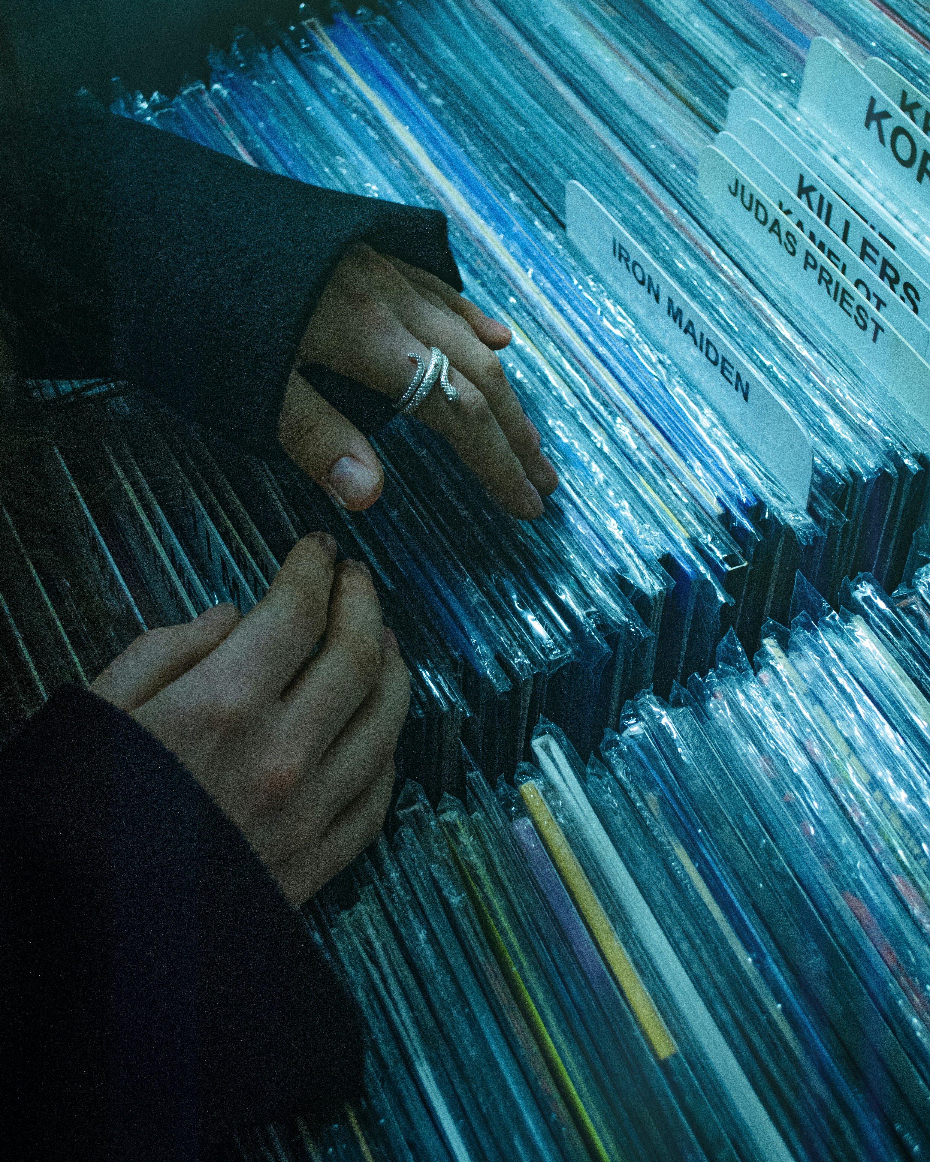 Hands sifting through vinyl records in a store.