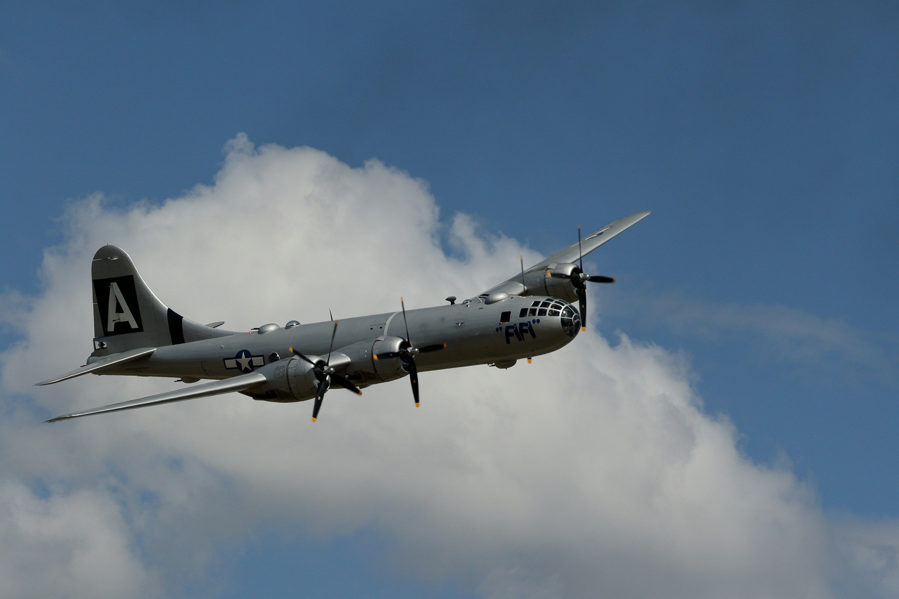 A vintage bomber aircraft flies in the sky.