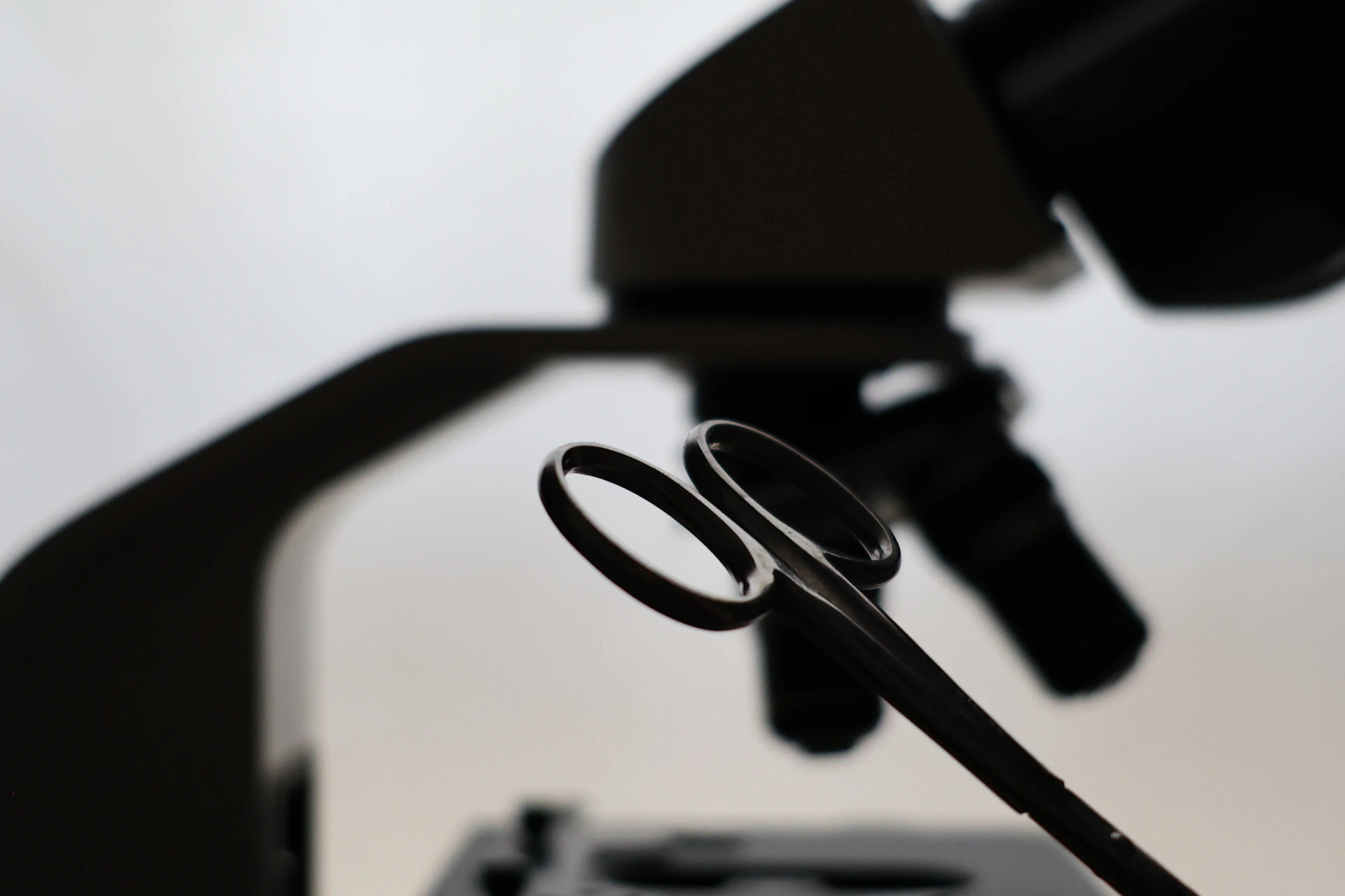 Microscope and scissors against a bright background