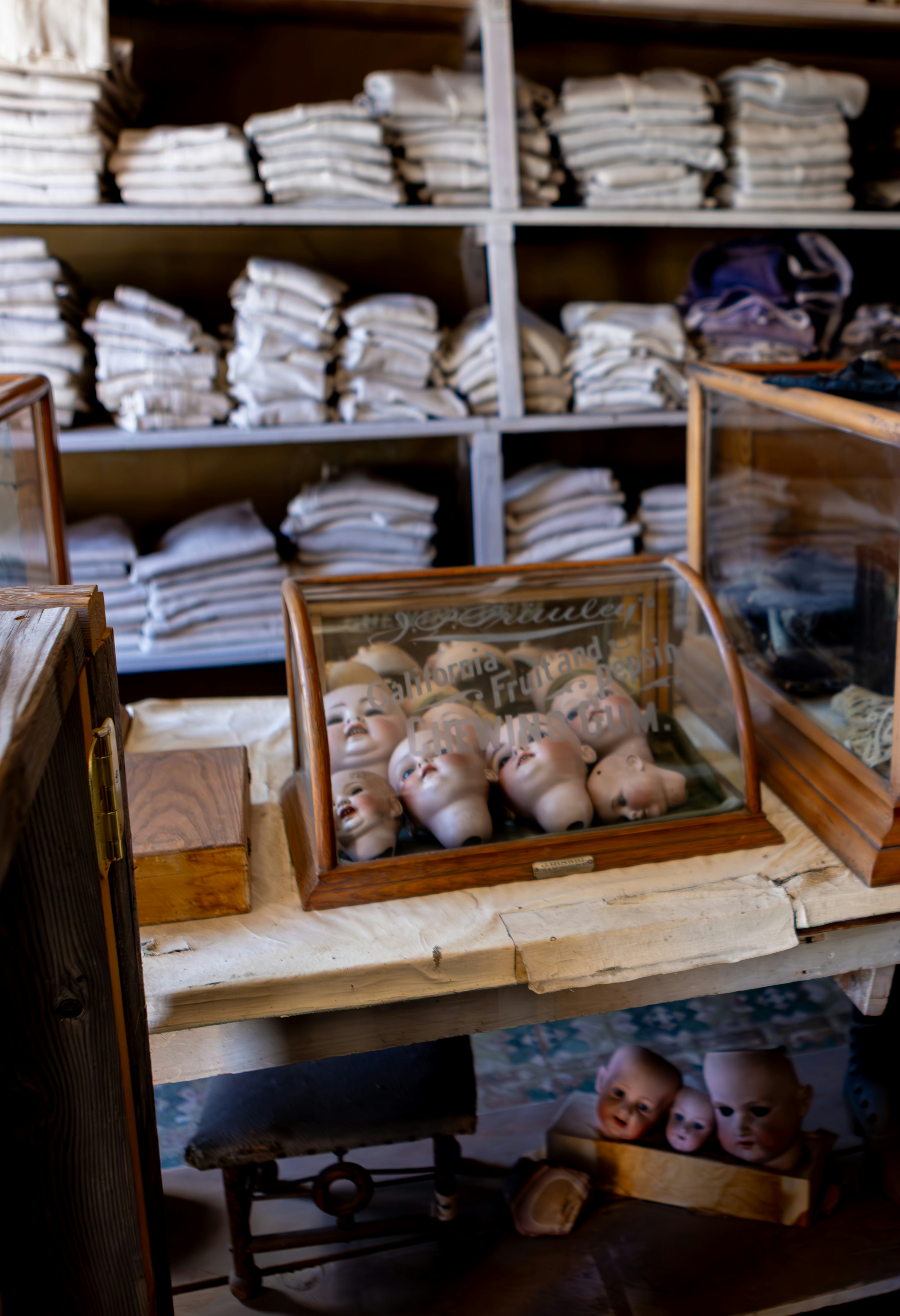 Antique doll heads displayed in a glass case.