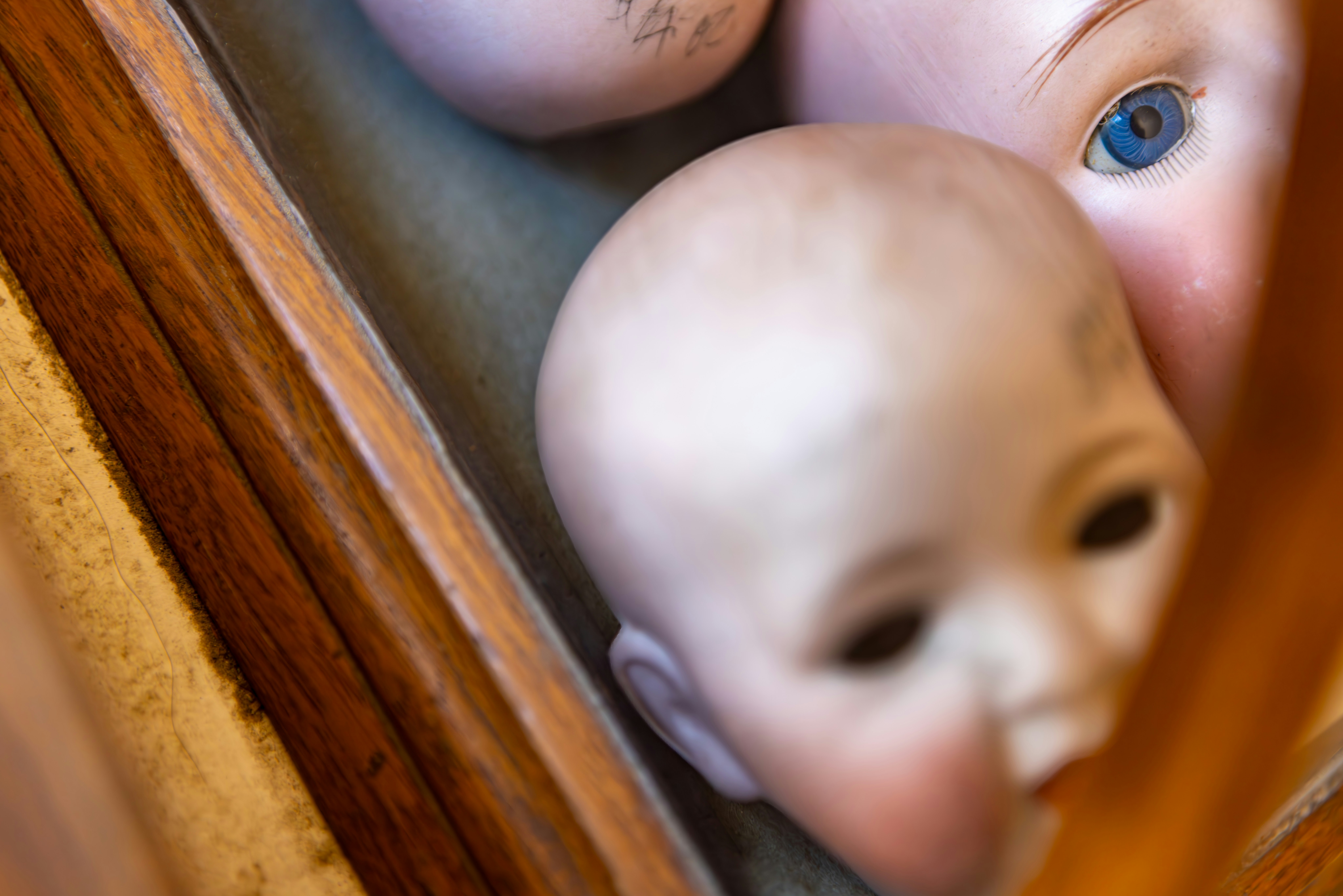 Several antique doll heads in a wooden box.