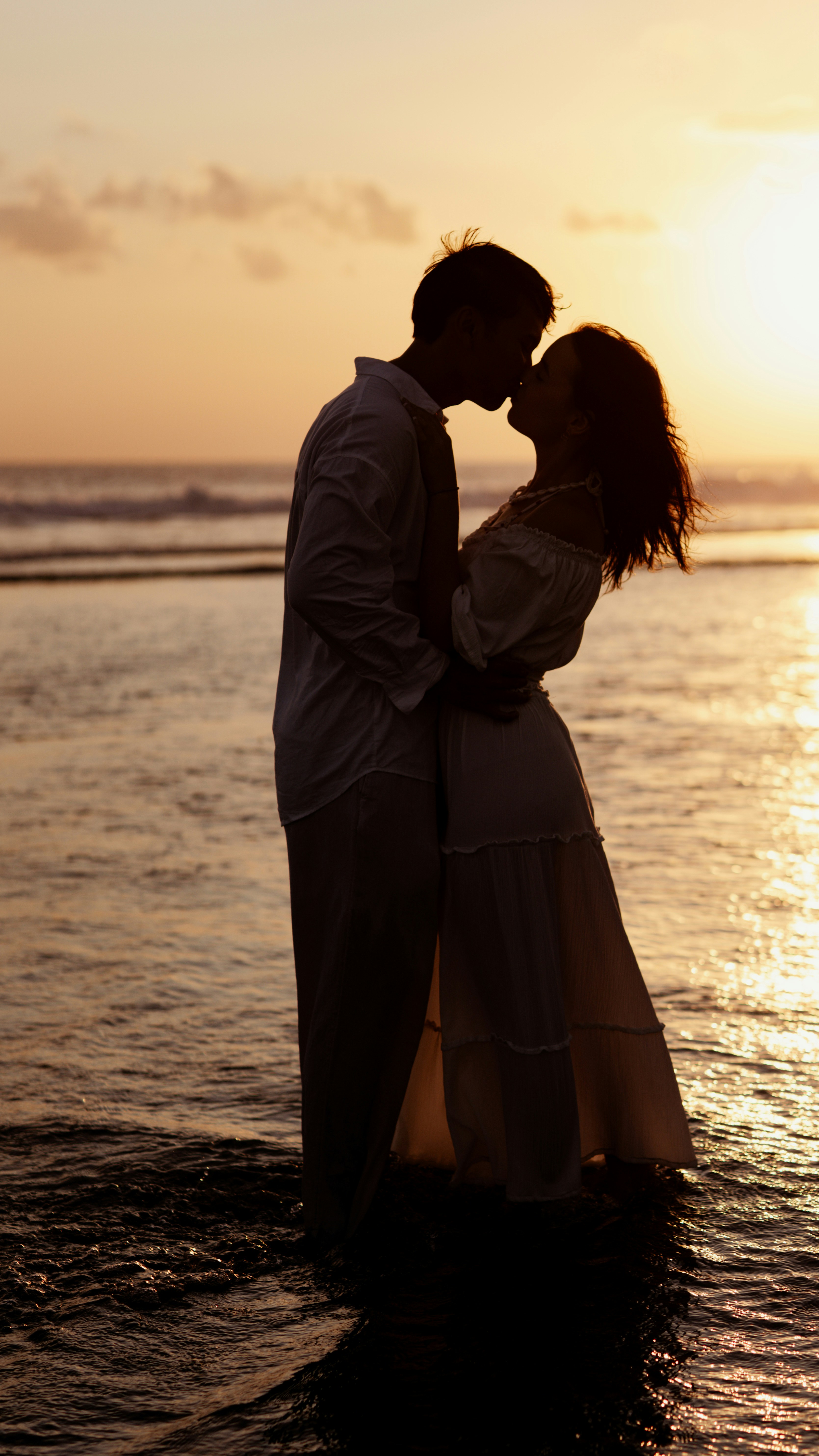 Couple kissing in the ocean at sunset