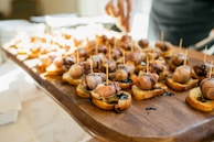 Wooden board filled with small appetizers on bread.