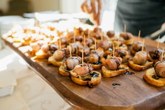 Wooden board filled with small appetizers on bread.