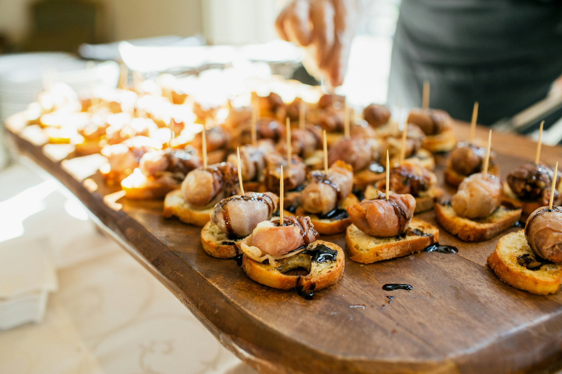 Wooden board filled with small appetizers on bread.